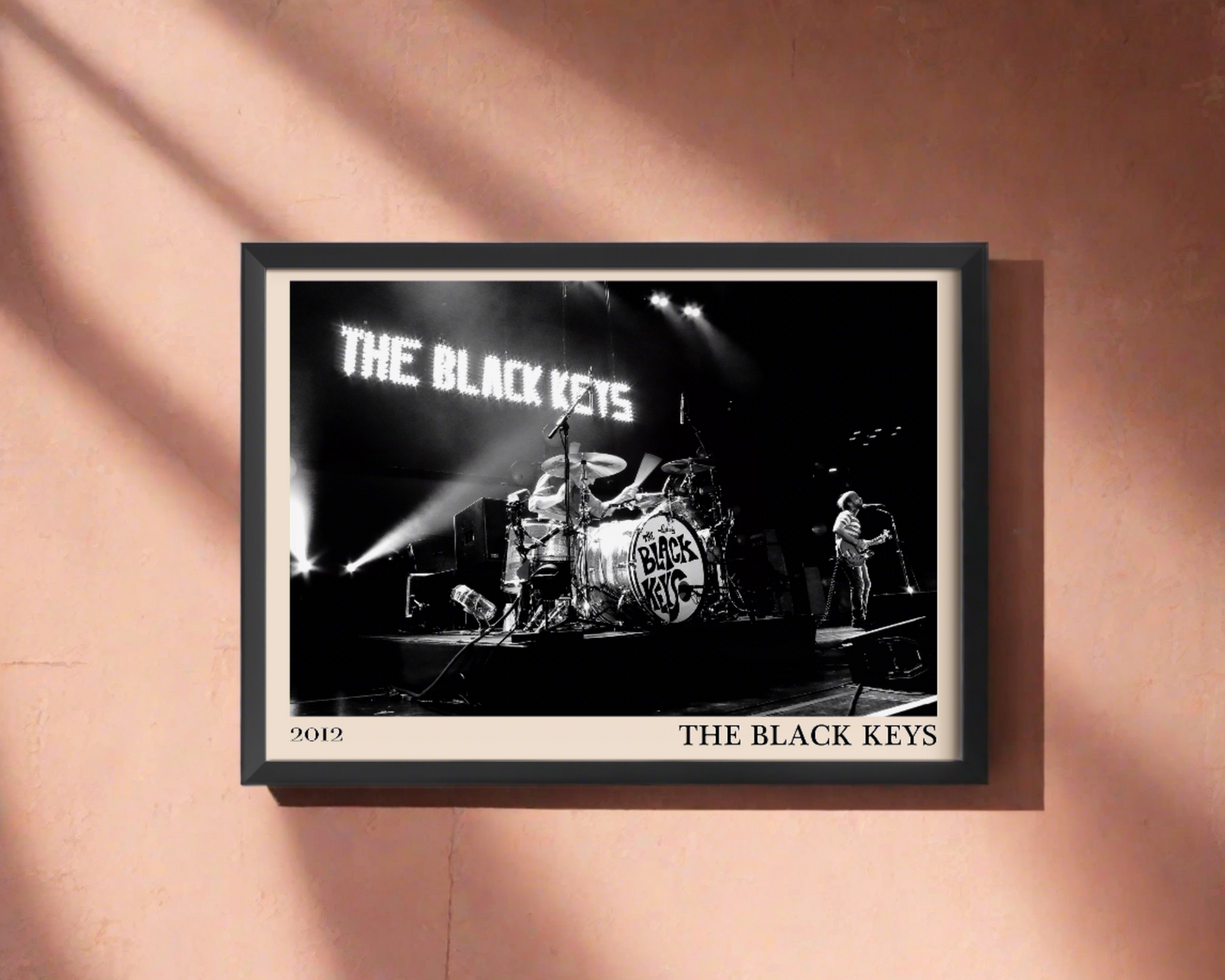 2012 photo of The Black Keys, crafted into an elegant black-framed print. Hanging on a burnt red wall