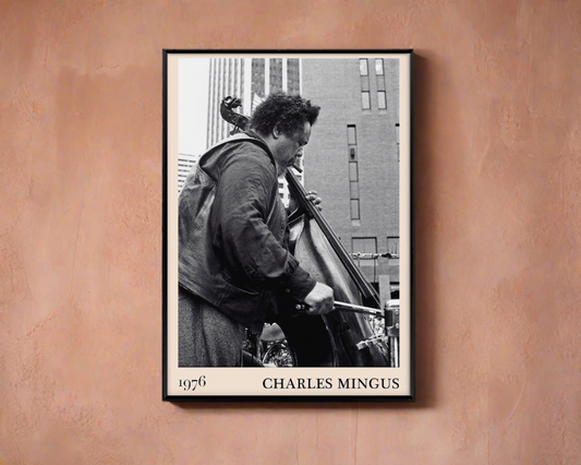1976 photograph of Charles Mingus taken by Thomas Marcello. Picture crafted into a black framed poster, with an off-white border. Poster is hanging on a peach-coloured wall