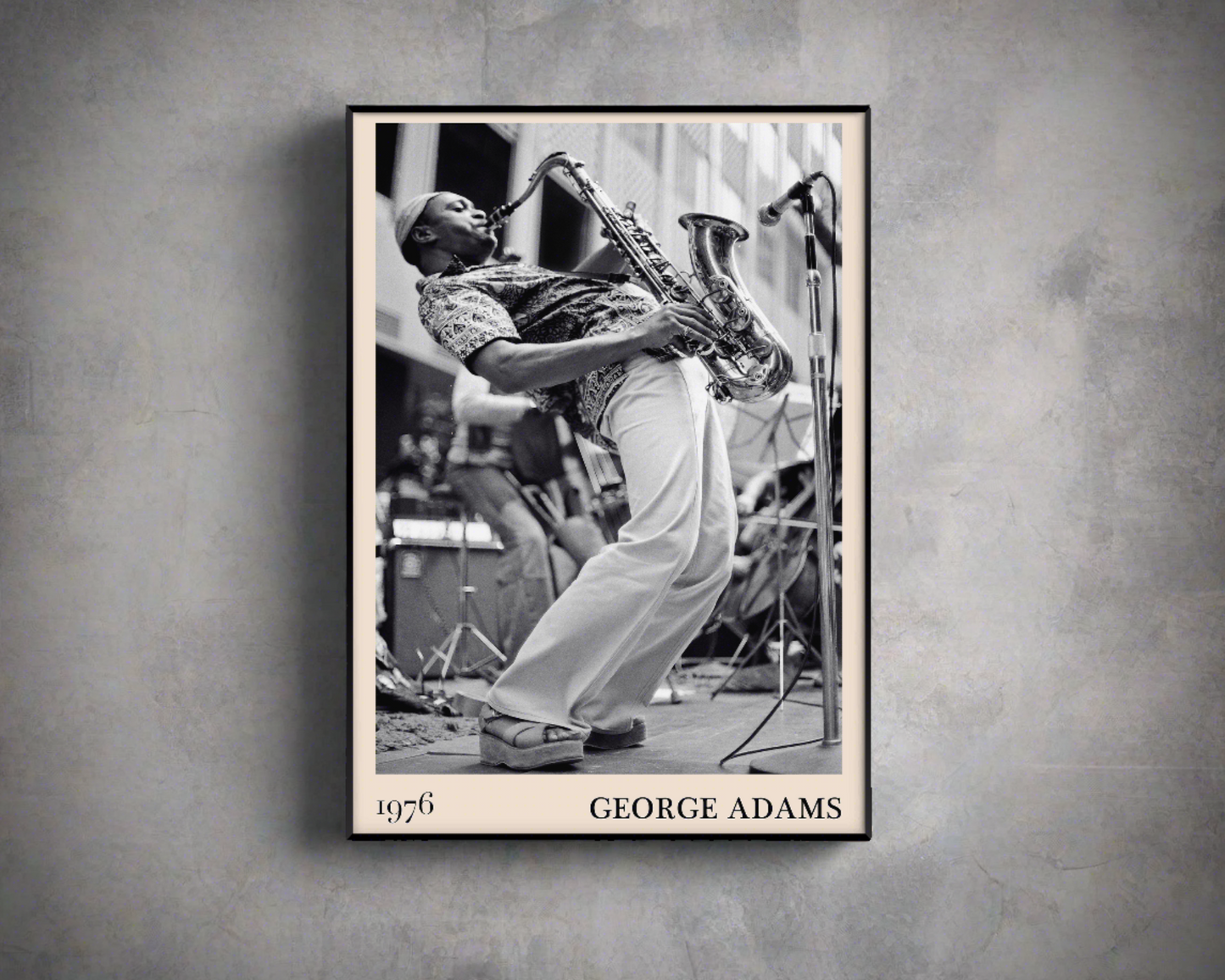 1976 photograph of George Adams taken by Thomas Marcello. Picture crafted into a black framed poster, with an off-white border. Poster is hanging on a grey wall