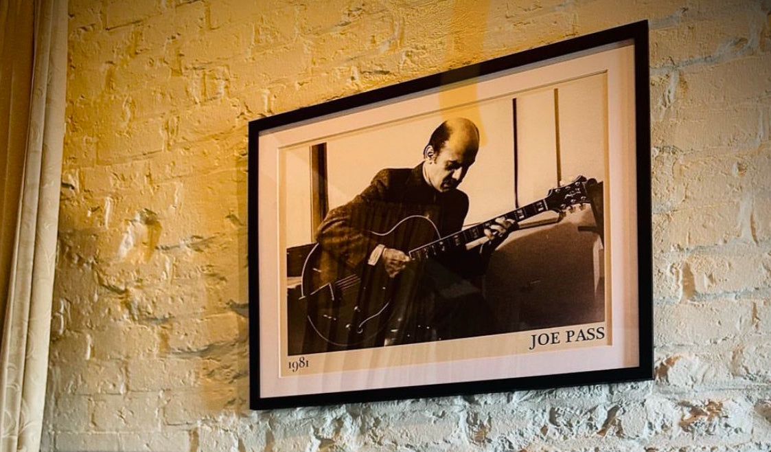 Framed poster of Joe Pass hanging on a white wall