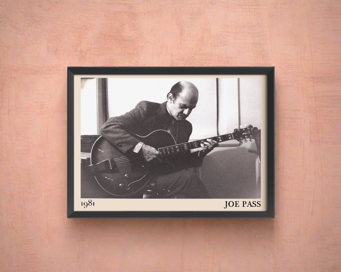 1981 photo of Joe Pass crafted into an elegant black-framed print. Hanging on a peach-coloured wall