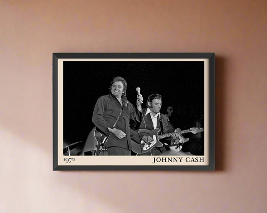 Iconic image of Johnny Cash performing, captured by Heinrich Klaffs and transformed into vintage-inspired wall decor hanging on a peach coloured rustic concrete wall in dappled sunlight
