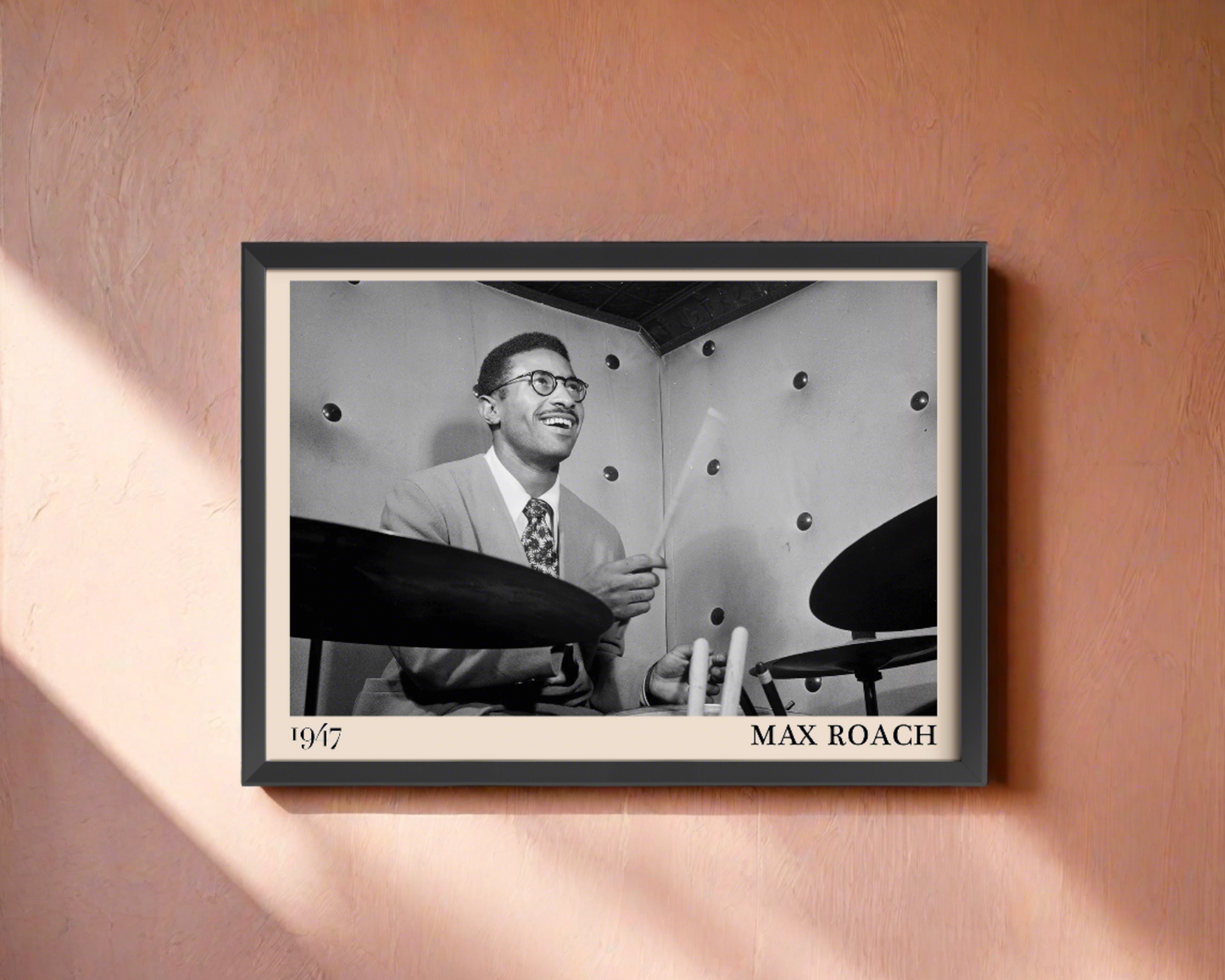 1947 photograph of Max Roach playing the drums, transformed into a stylish black-framed jazz poster hanging on a coral coloured wall