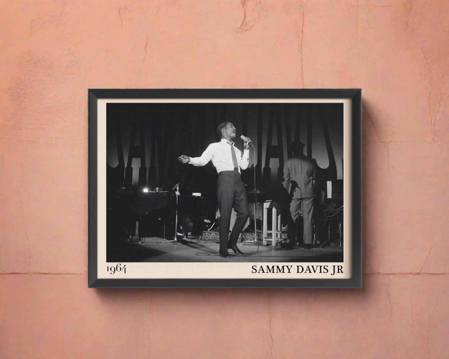 1964 picture of Sammy Davis Jr. Picture crafted into a black framed poster, with an off-white border. Poster is hanging on a peach wall