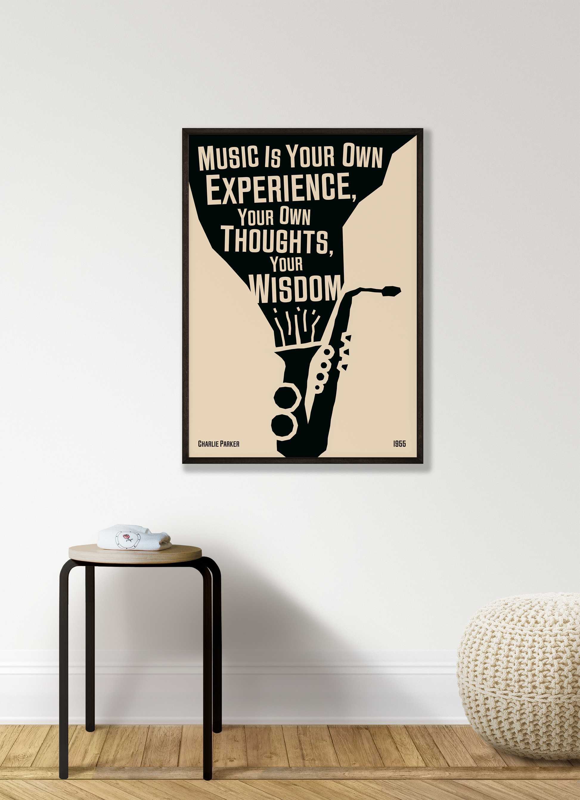 A poster featuring a black and white illustration of a saxophone with a quote by Charlie Parker, titled 'Music Is Your Own Experience, Your Own Thoughts, Your Wisdom', hanging on a white living room wall