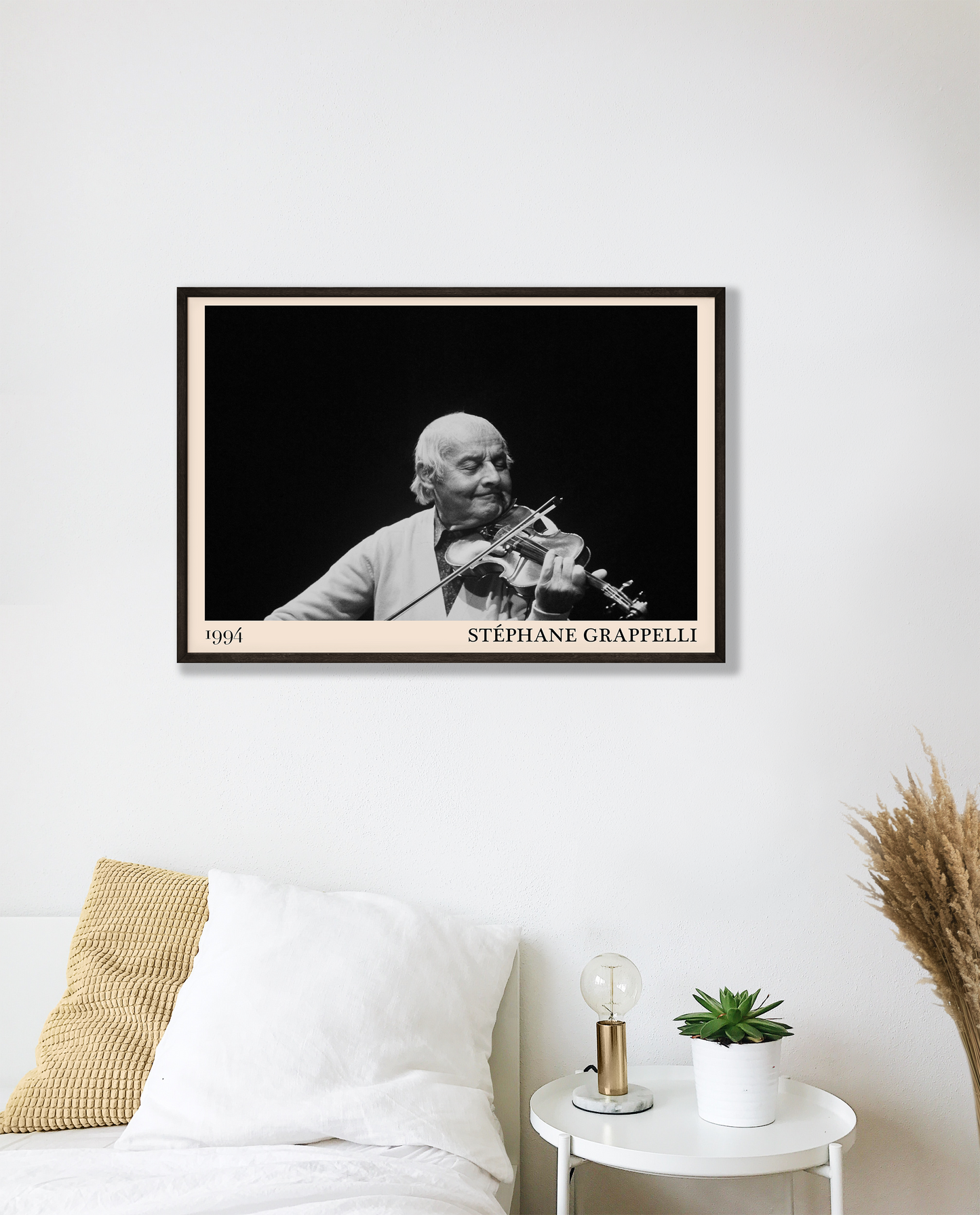 Black framed poster of Stephan Grappelli hanging on a white bedroom wall.
