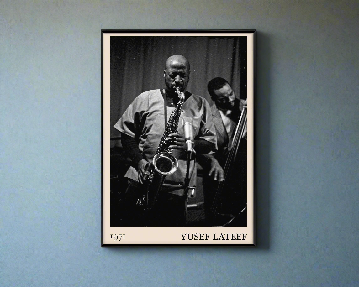 1971 photo of Yusef Lateef crafted into a black framed-poster, hanging on a blue rustic concrete wall in dappled sunlight
