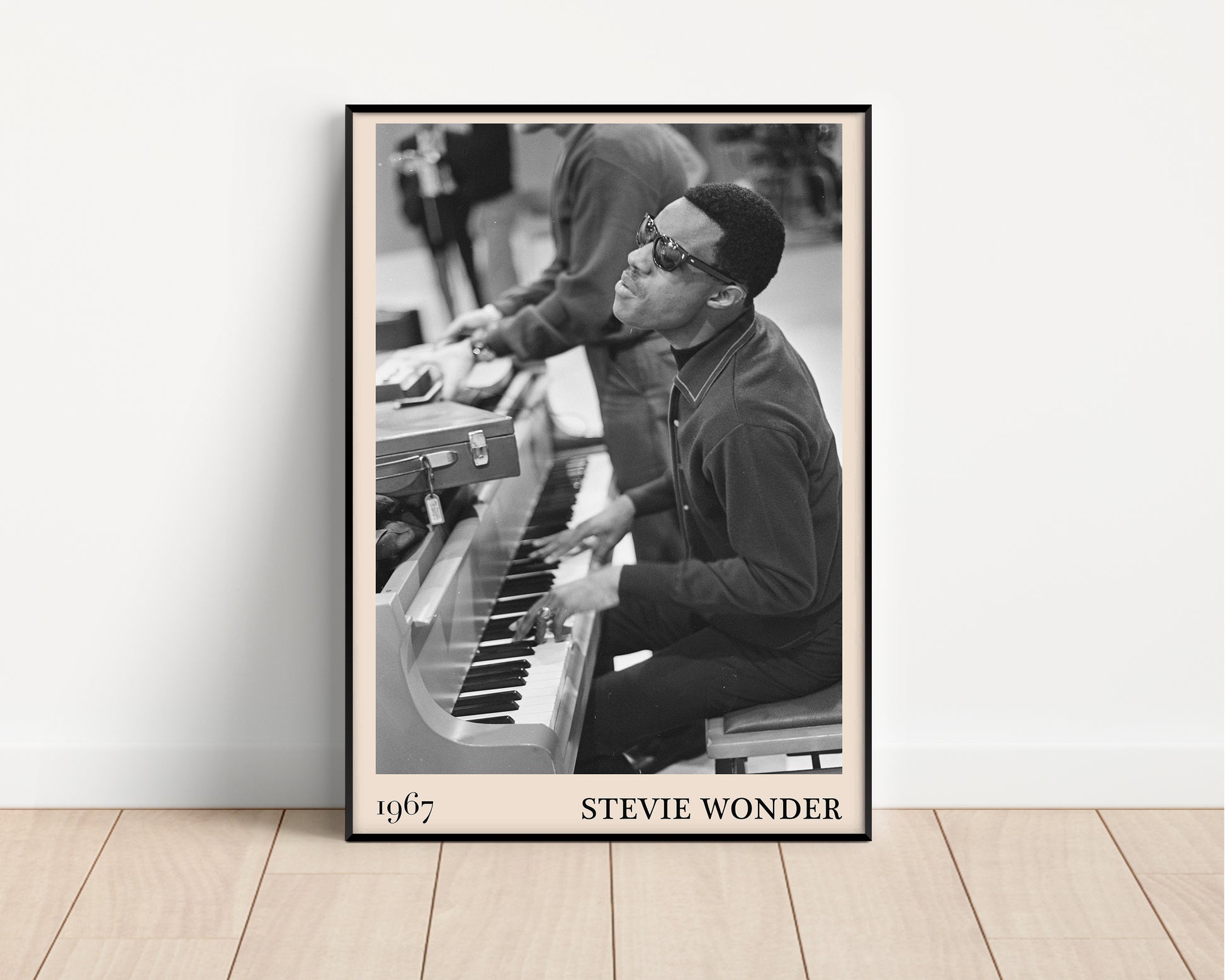 1967 photo of Stevie Wonder, crafted into an elegant black-framed print. leaning against a white wall