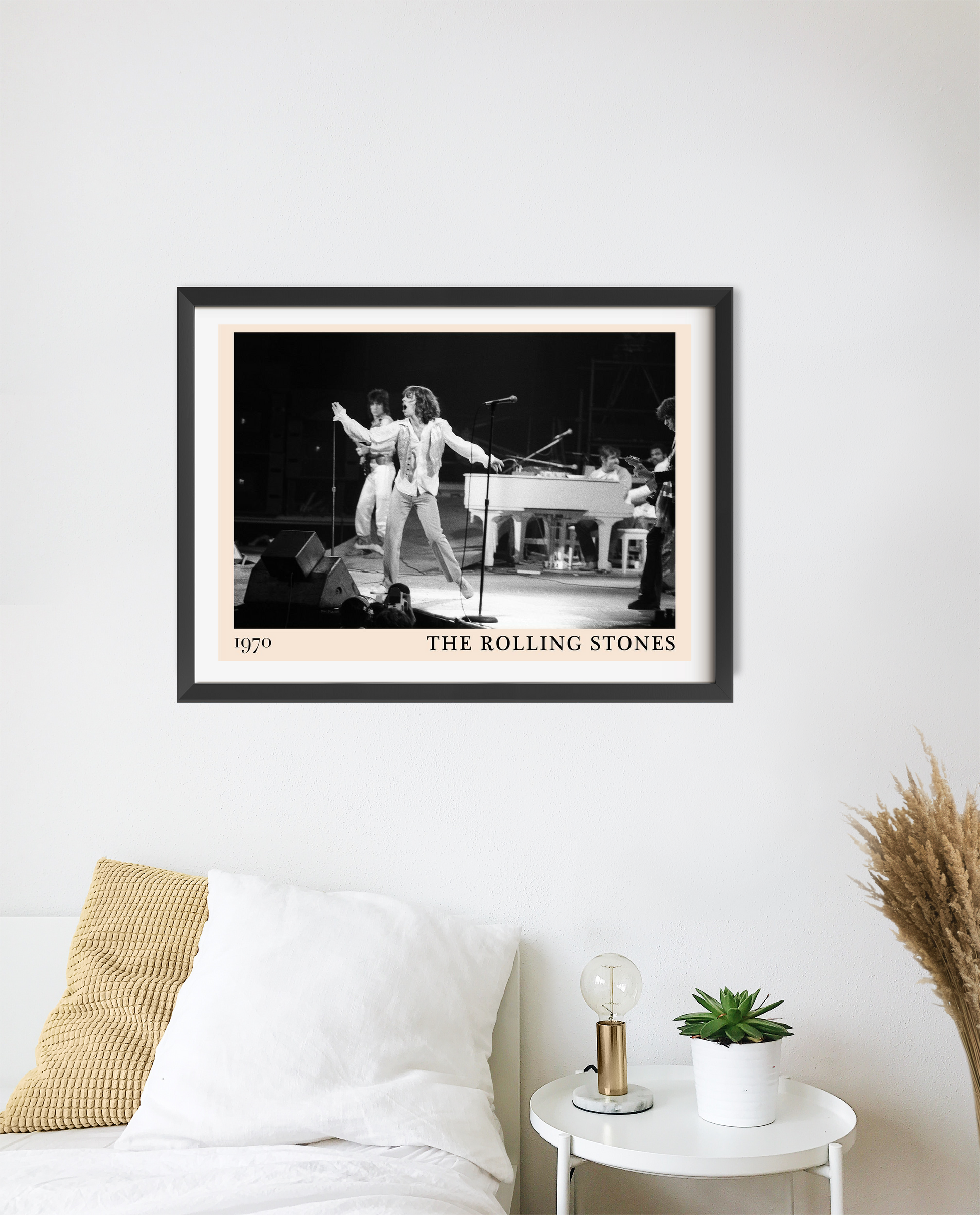The Rolling Stones retro concert poster in landscape mount mockup, black-and-white stage photo above a modern white bed.