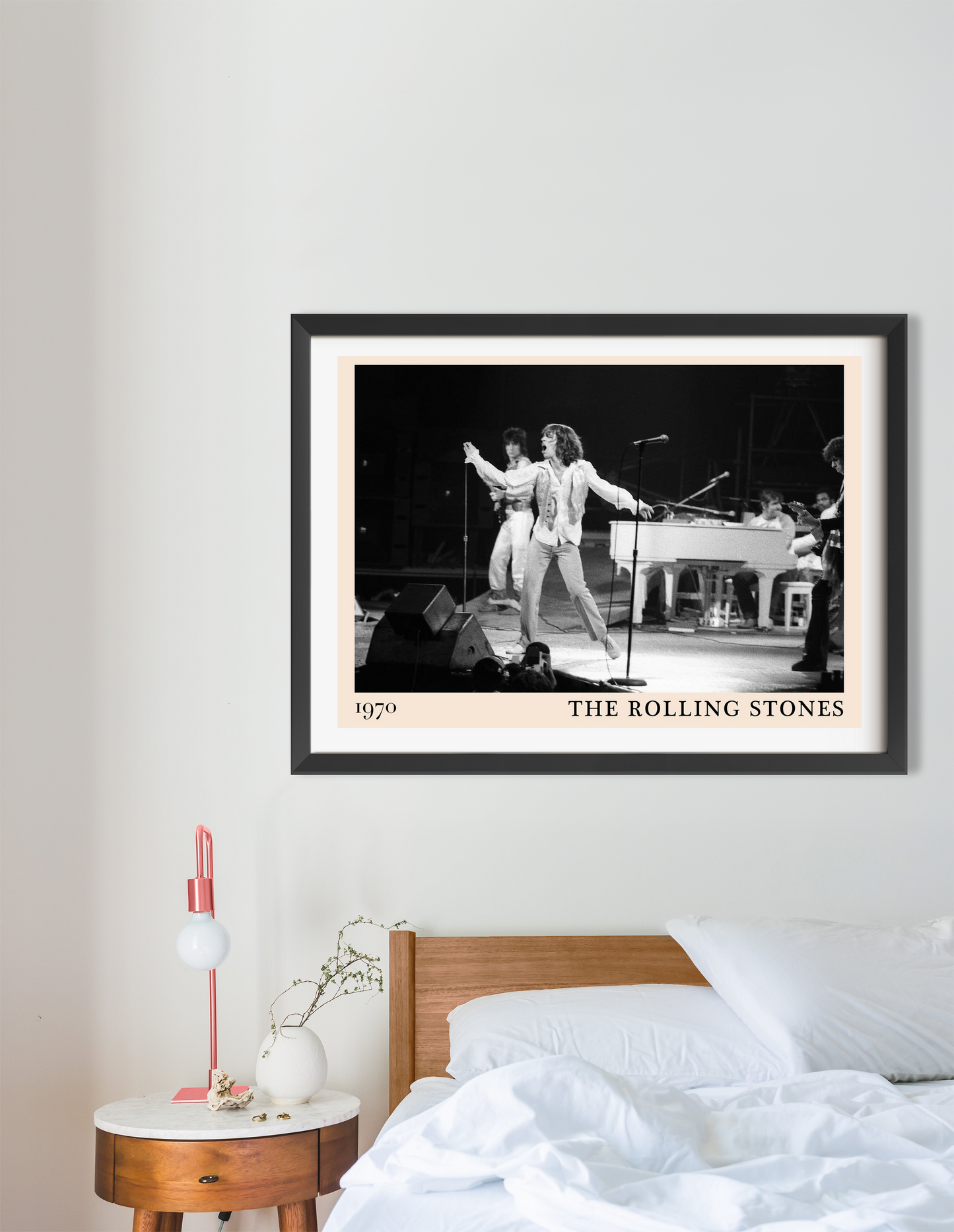 The Rolling Stones Retro Concert Poster in a black frame, landscape 16 mount, displayed above a modern wooden bed in a cozy b