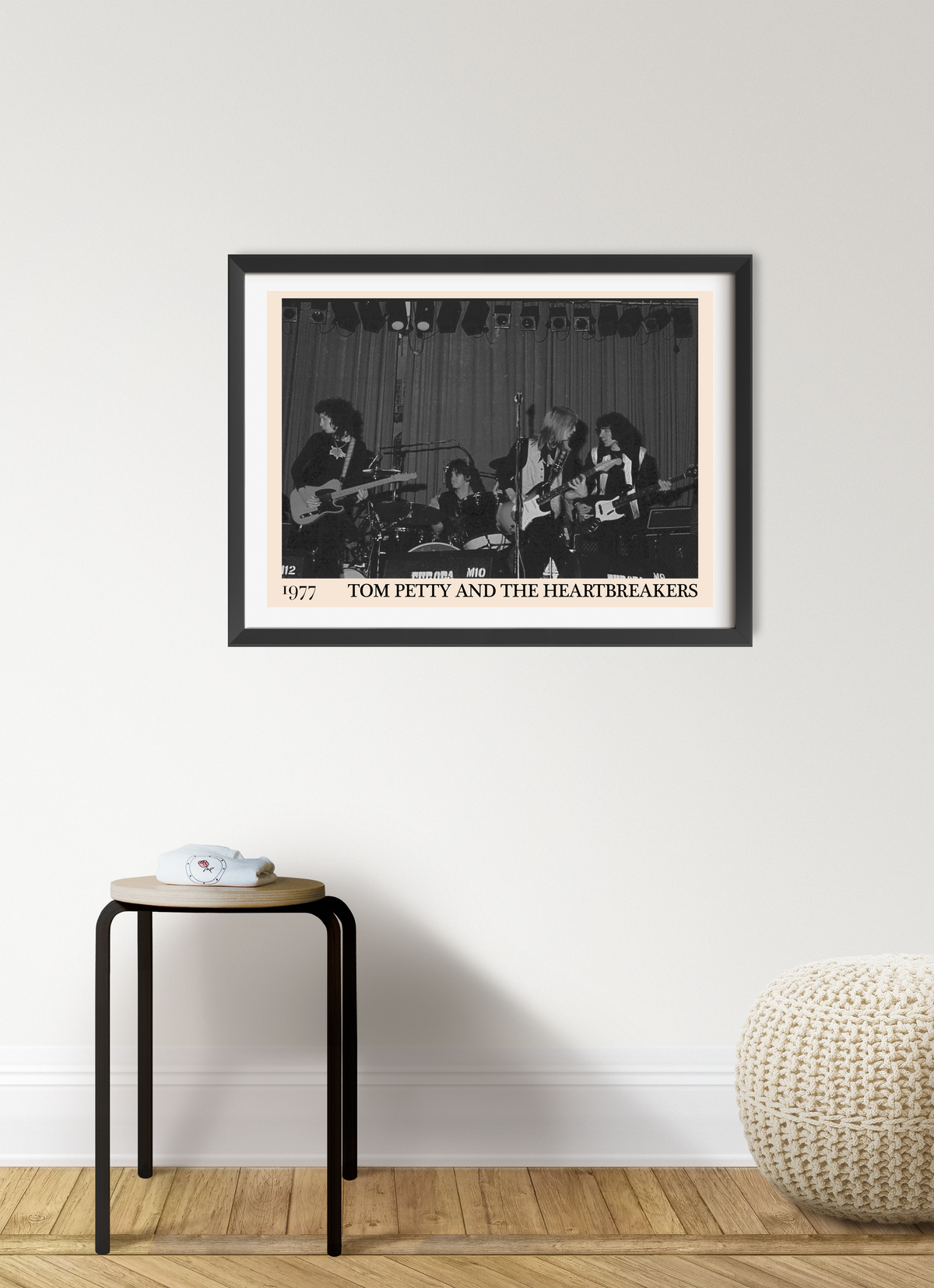 Framed print of Tom Petty and the Heartbreakers performing live in 1977, shown in a black frame on a white wall above a