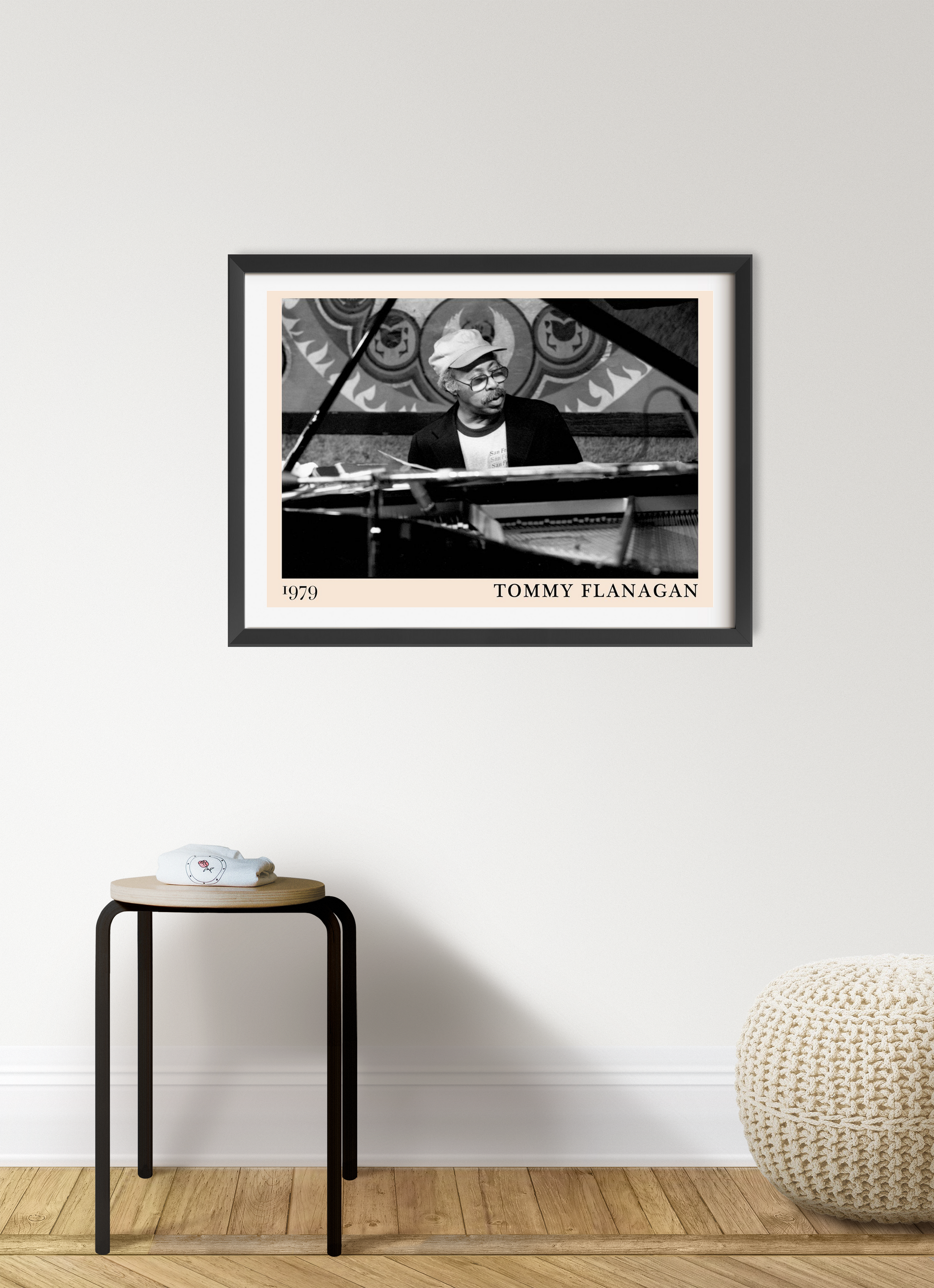 Tommy Flanagan landscape wall art mockup in modern living room, black and white framed print above wooden stool and pouf.