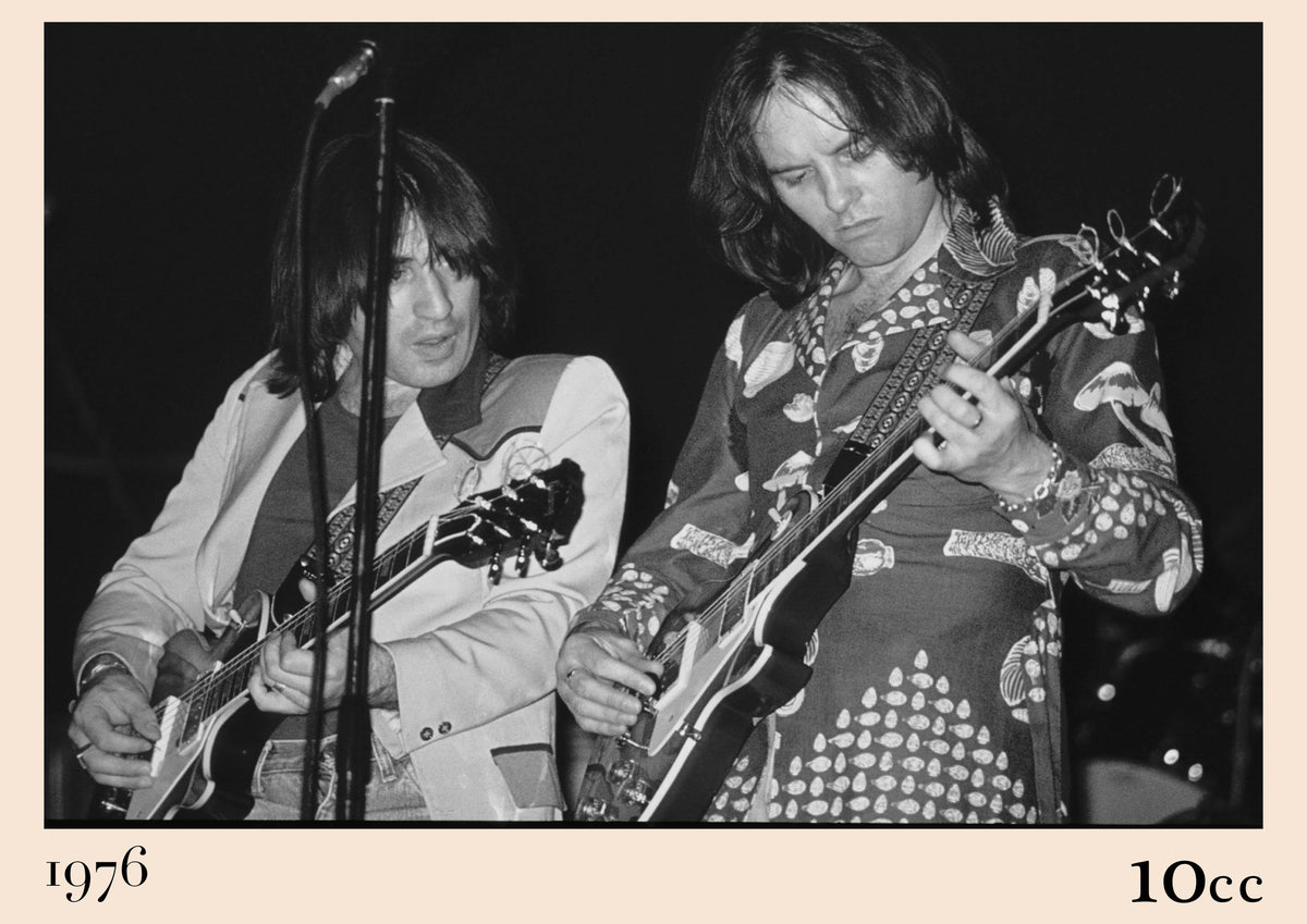 Black and white photo of 10cc's Eric Stewart and Lol Creme playing electric guitars on stage, captioned 1976 and 10cc