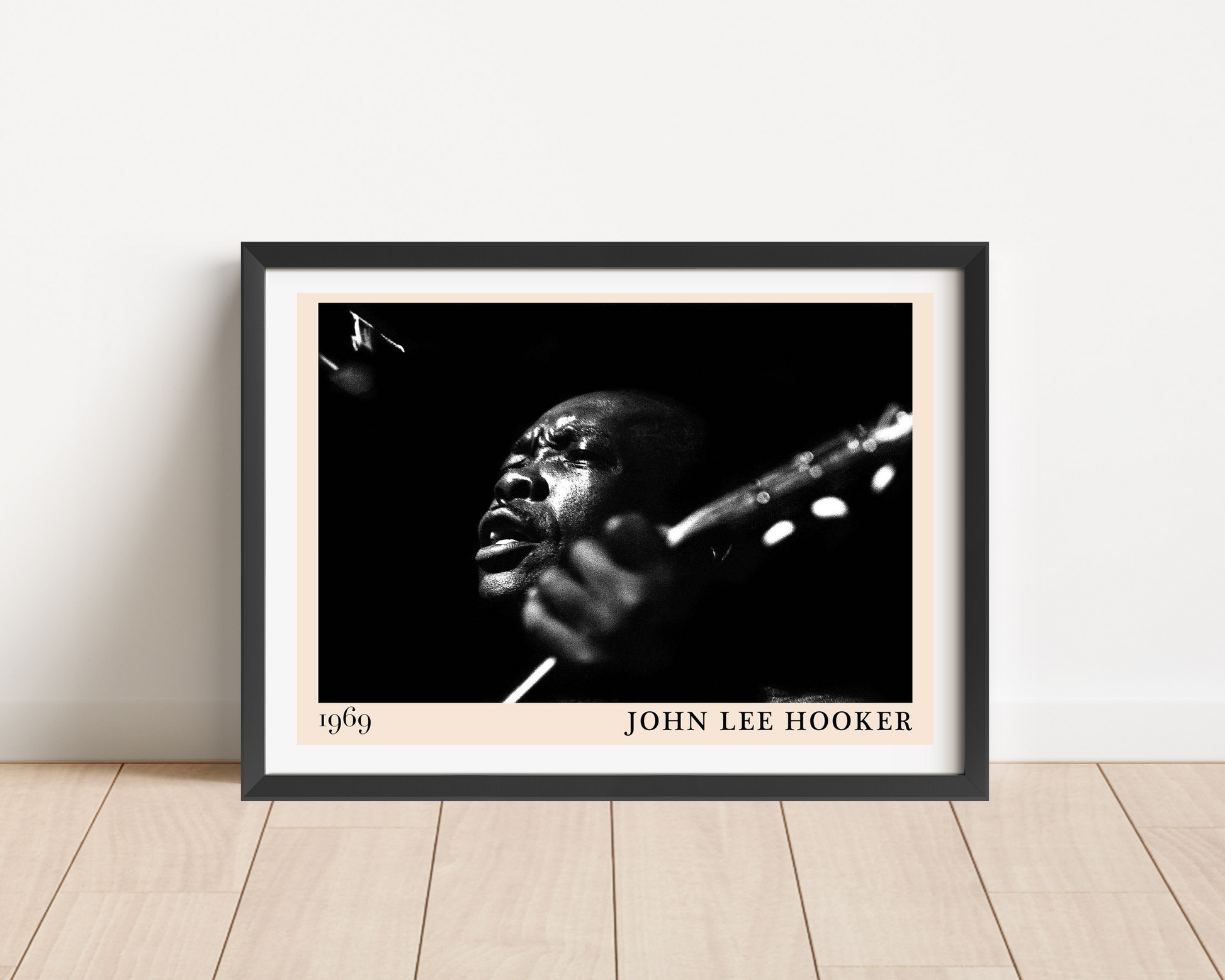 John Lee Hooker Retro Blues Poster in a black frame, landscape mount on wood floor, features bold black-and-white portrait de