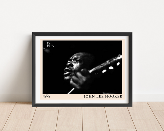 John Lee Hooker Retro Blues Poster in a black frame, landscape mount on wood floor, features bold black-and-white portrait de
