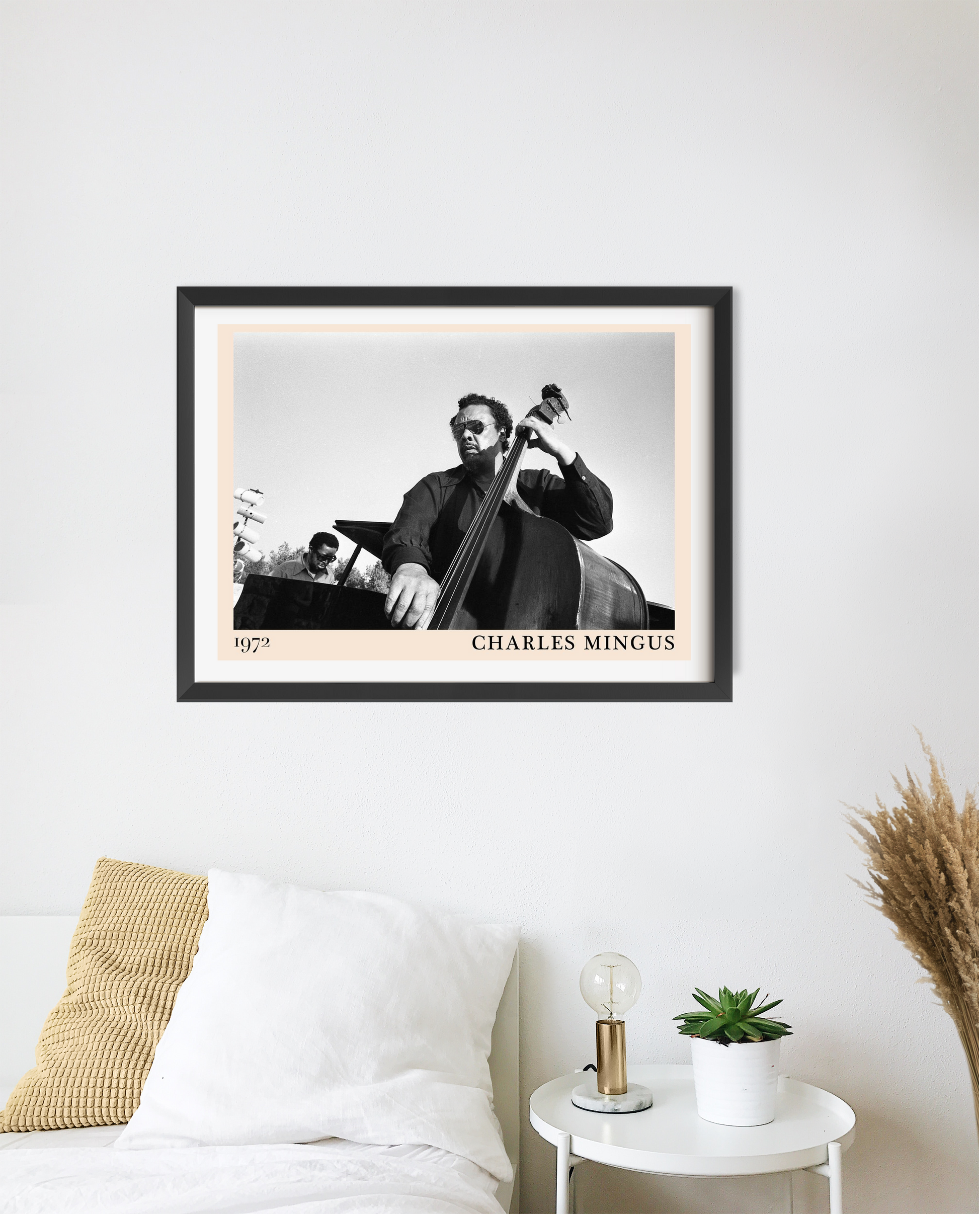 Charles Mingus Cool Jazz Poster in black frame displayed above a bed, featuring a vintage jazz musician design in a modern be