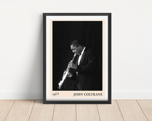 John Coltrane jazz poster mockup in a modern black frame on a wood floor, featuring a black and white saxophone portrait.