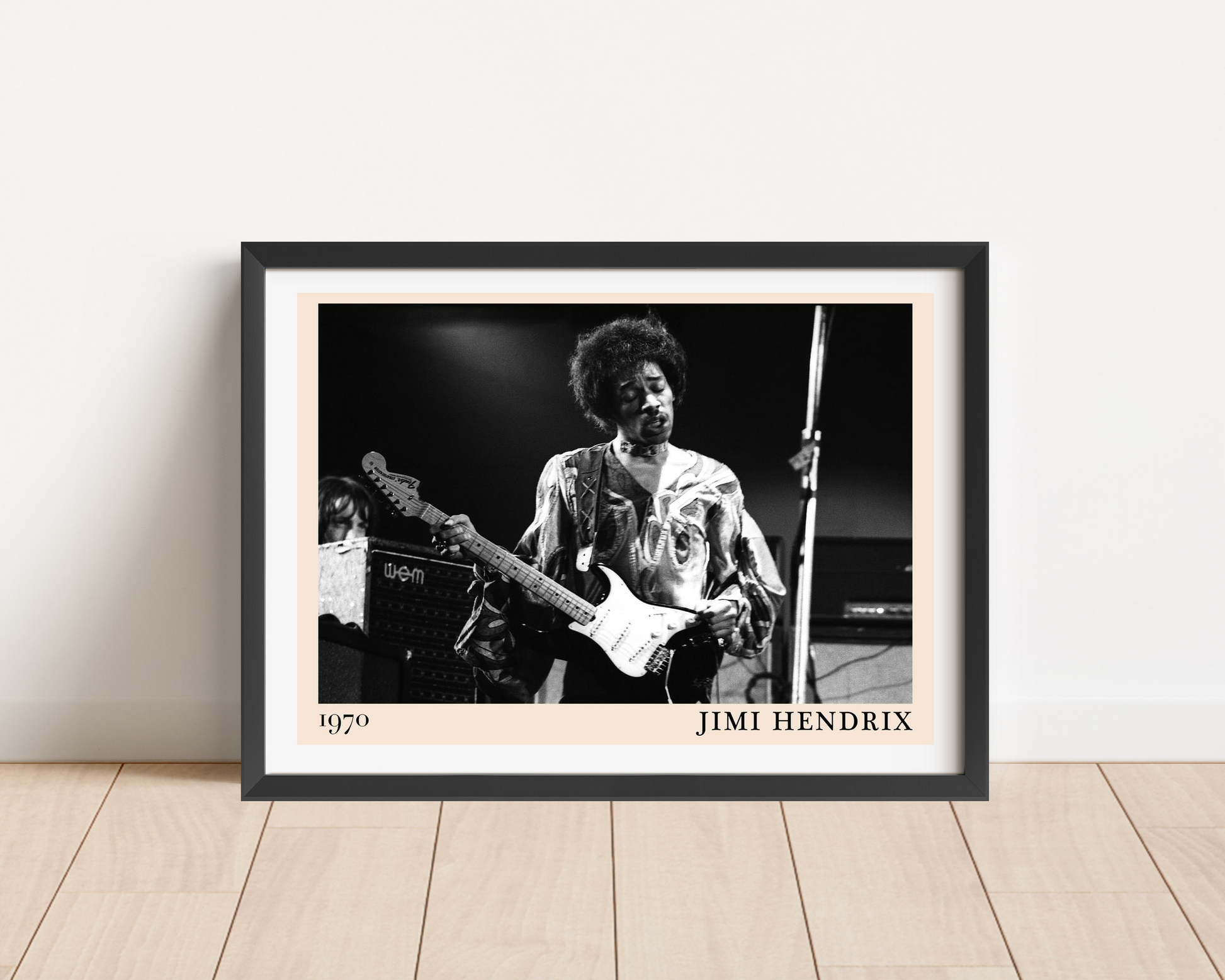 Jimi Hendrix Retro Concert Poster in a landscape frame mockup, black and white 1970 guitar photo on wood floor against wall.