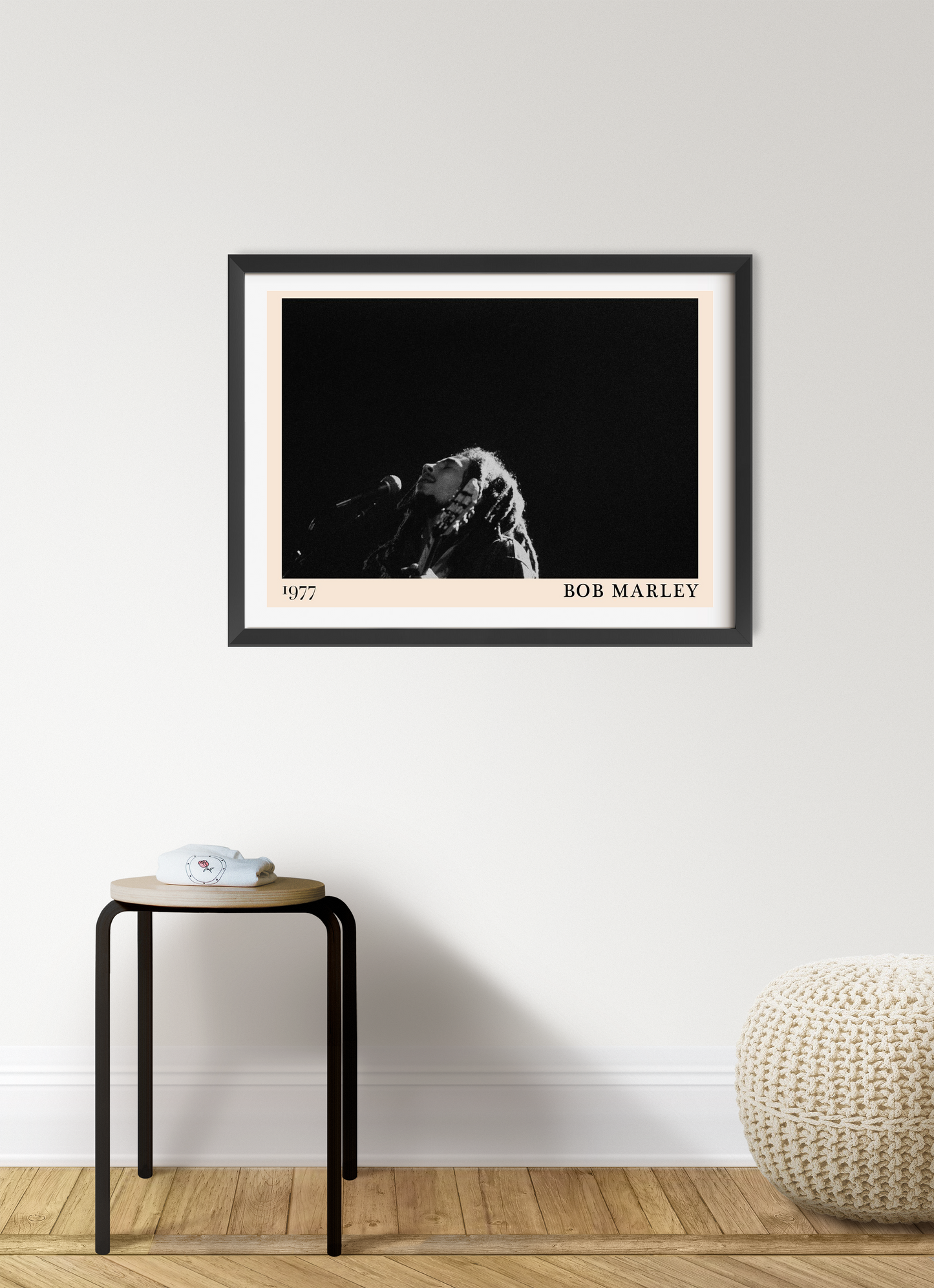 Bob Marley concert poster in landscape mount mockup, black and white design, framed on modern living room wall above stool.