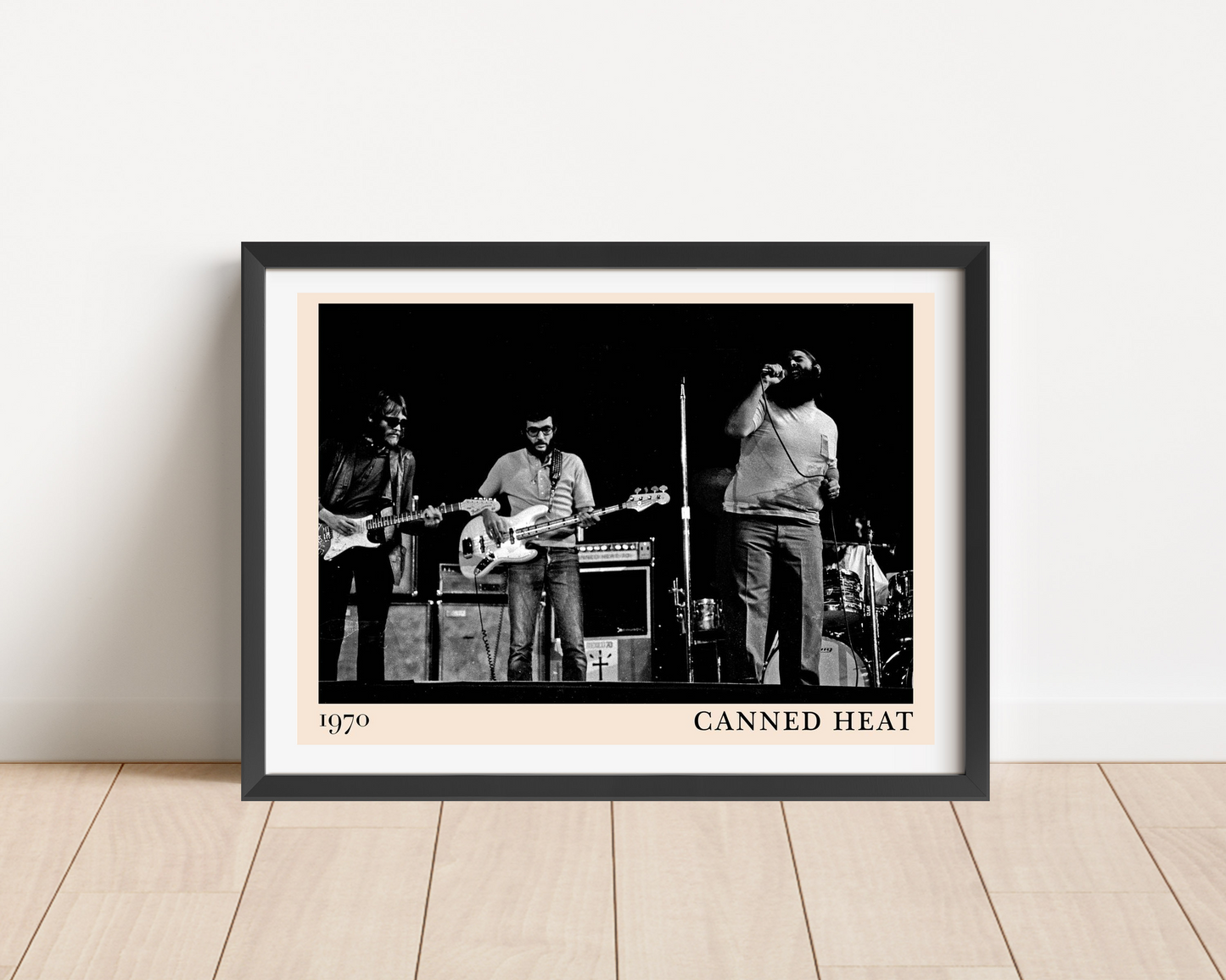 Canned Heat poster in landscape main mount mockup, black frame on wood floor, vintage 1970 band photo with bold text.