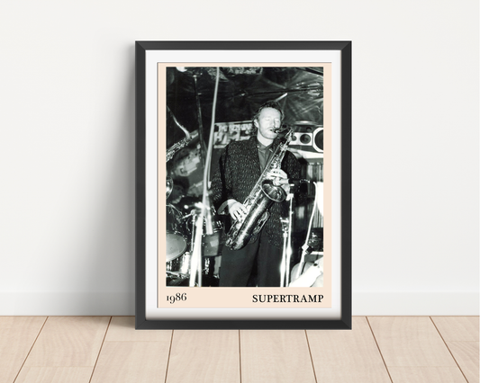 Framed Supertramp 1986 concert print leaning against a white wall on light wood flooring, featuring a black and white photo