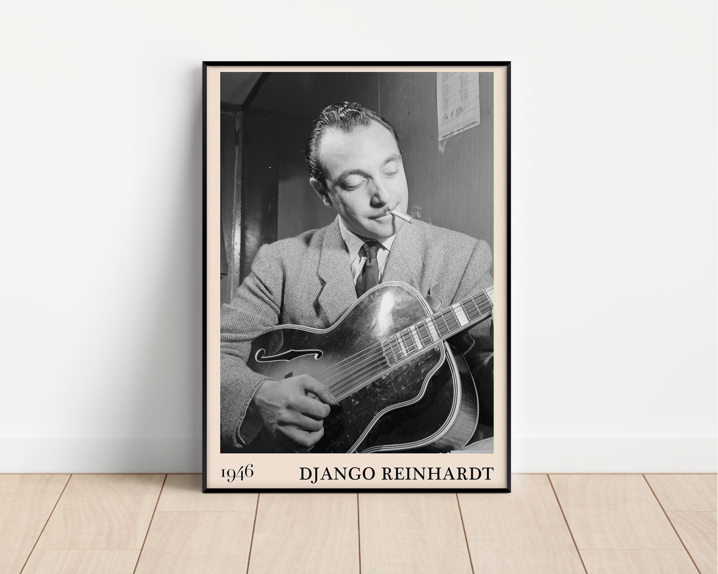1946 photograph of Django Reinhardt playing the guitar. Transformed into a stylish black-framed jazz poster resting against a white wall