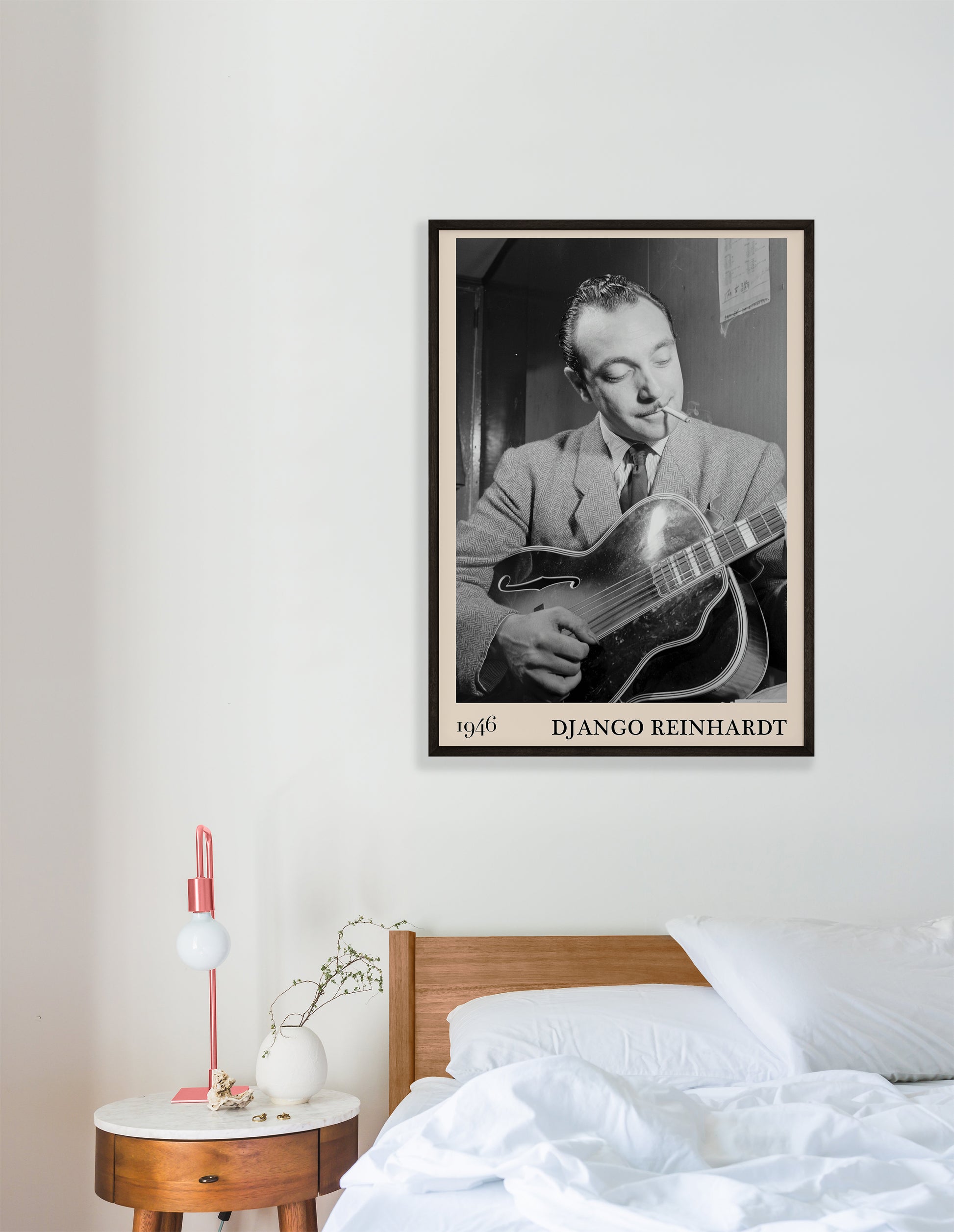 1946 photograph of Django Reinhardt playing the guitar. Transformed into a retro black-framed jazz poster hanging on a white bedroom wall
