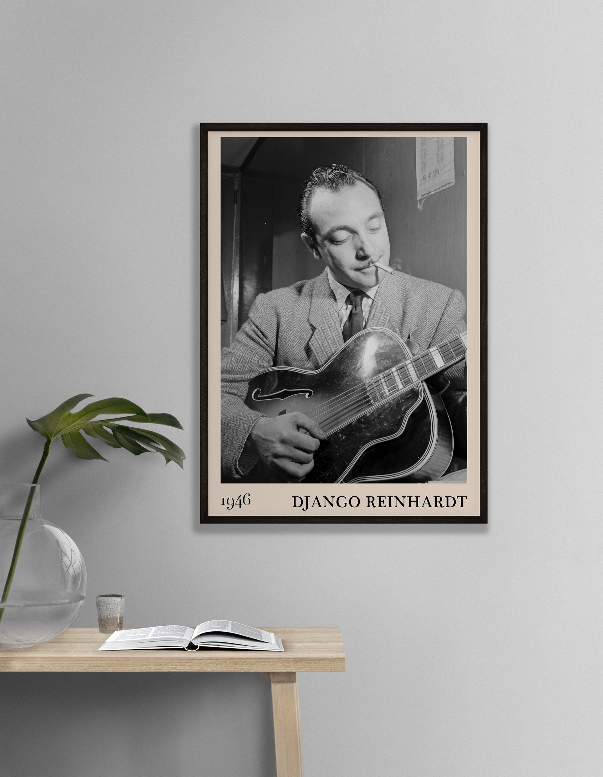 1946 photograph of Django Reinhardt playing the guitar. Transformed into a stylish black-framed jazz poster hanging on a grey living room wall