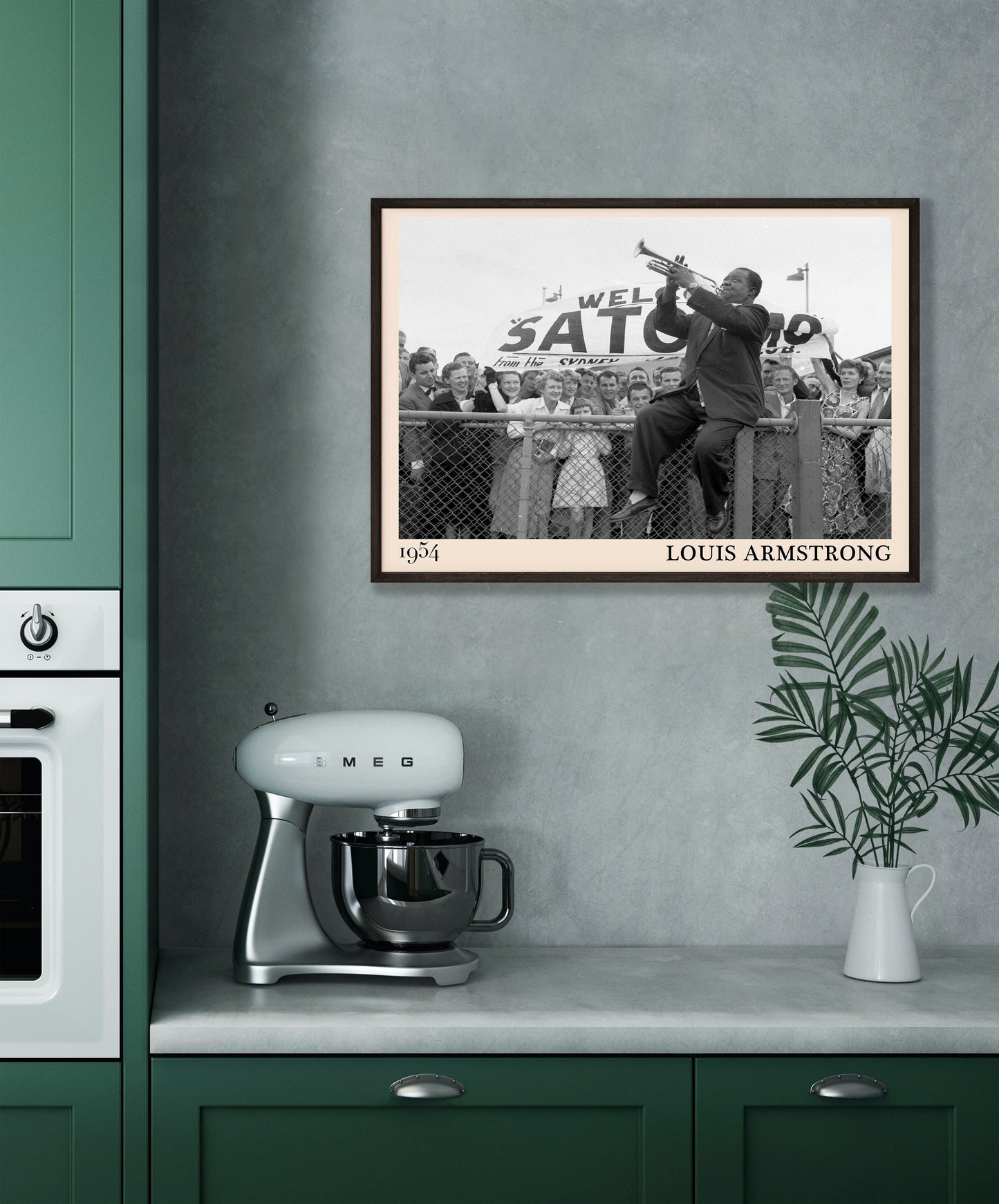1954 picture of Louis Armstrong playing his trumpet sat on a fence. Picture crafted into a cool black framed music print, with an off-white border. Poster is hanging on a grey kitchen wall.