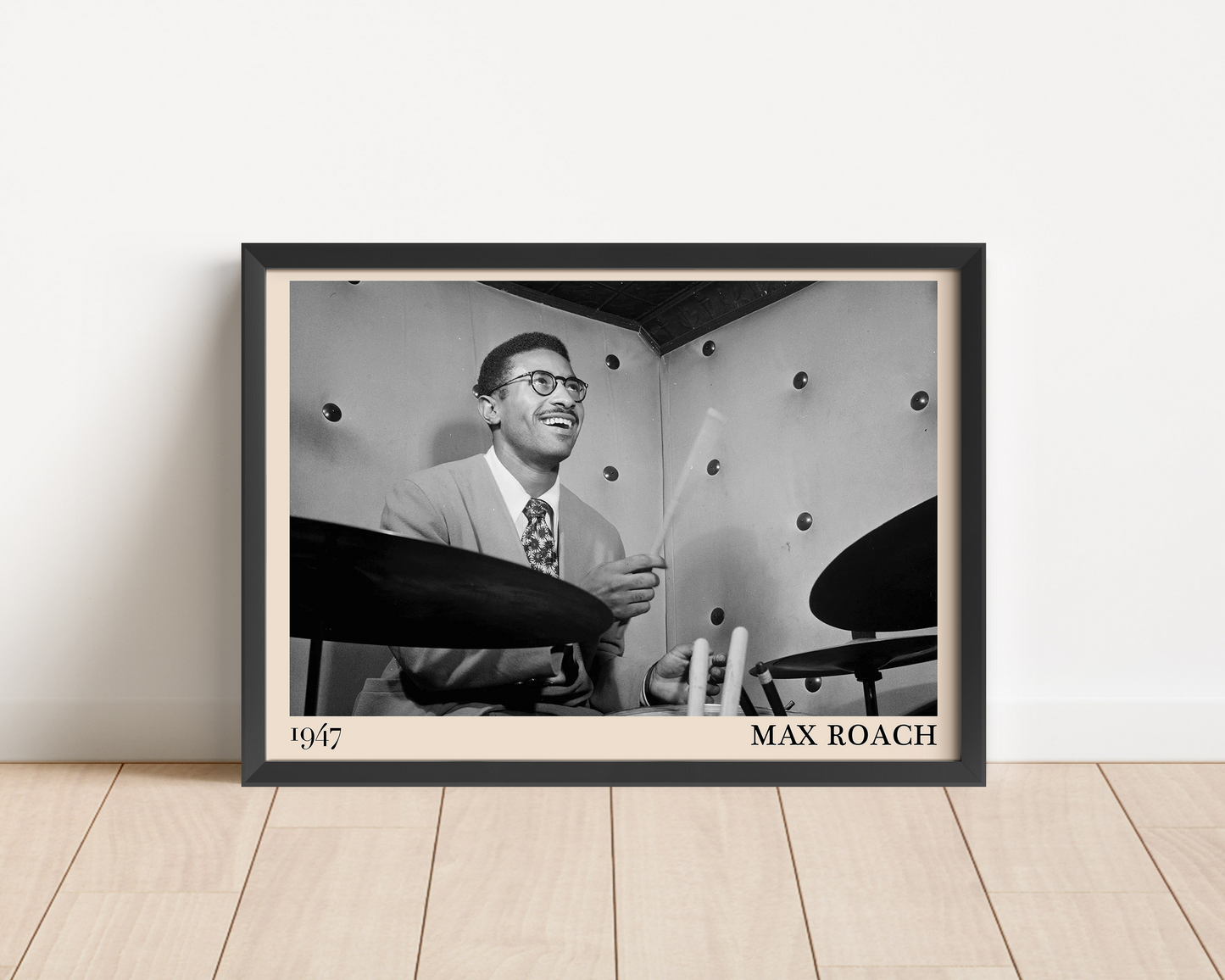 1947 photograph of Max Roach playing the drums, transformed into a stylish black-framed jazz poster leaning on a white wall