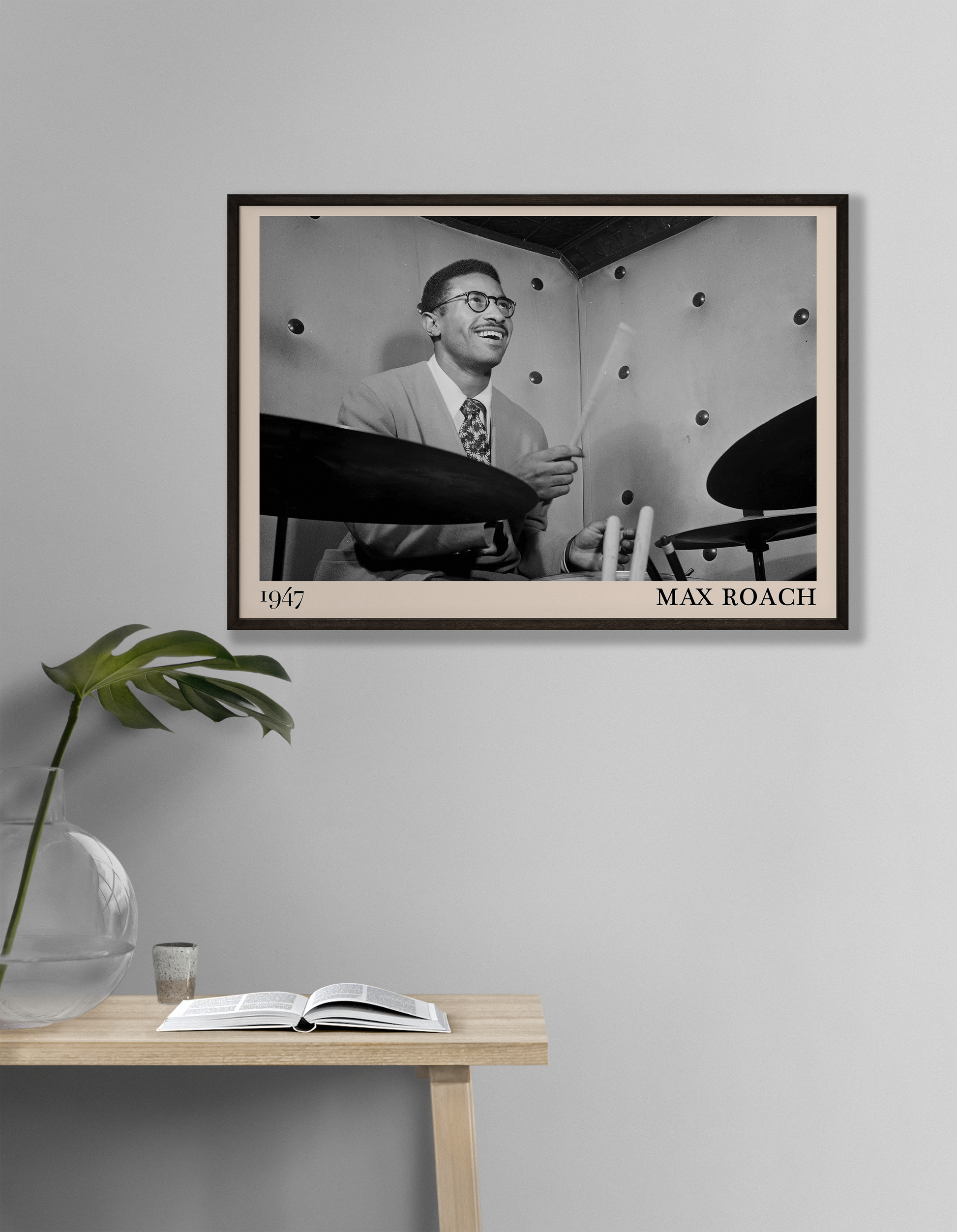 1947 photograph of Sonny Rollins playing the drums, transformed into a retro black-framed jazz poster hanging on a grey living room wall