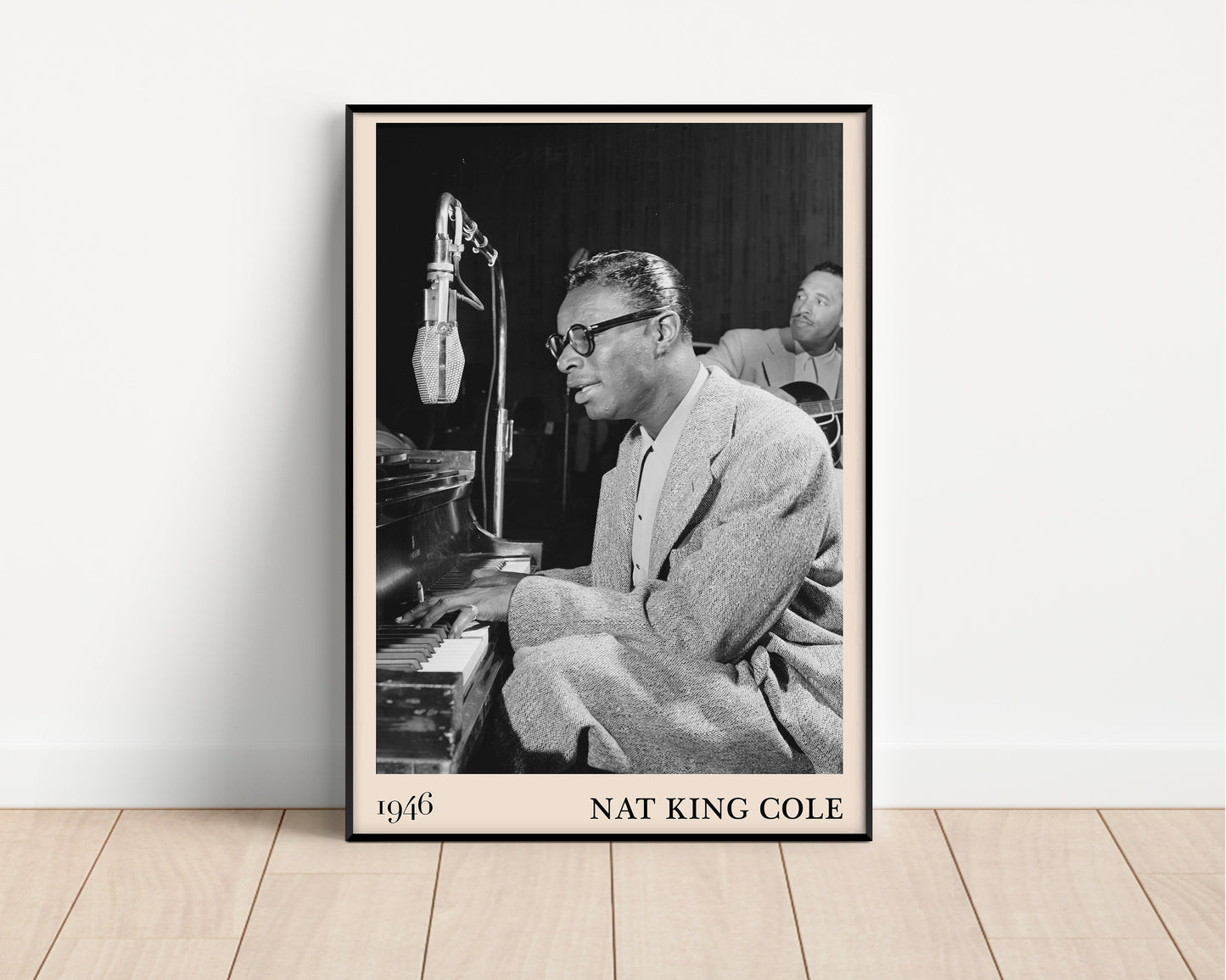 1946 picture of Nat King Cole playing a piano and singing. Picture crafted into a black framed poster, with an off-white border. Poster is propped against a white wall