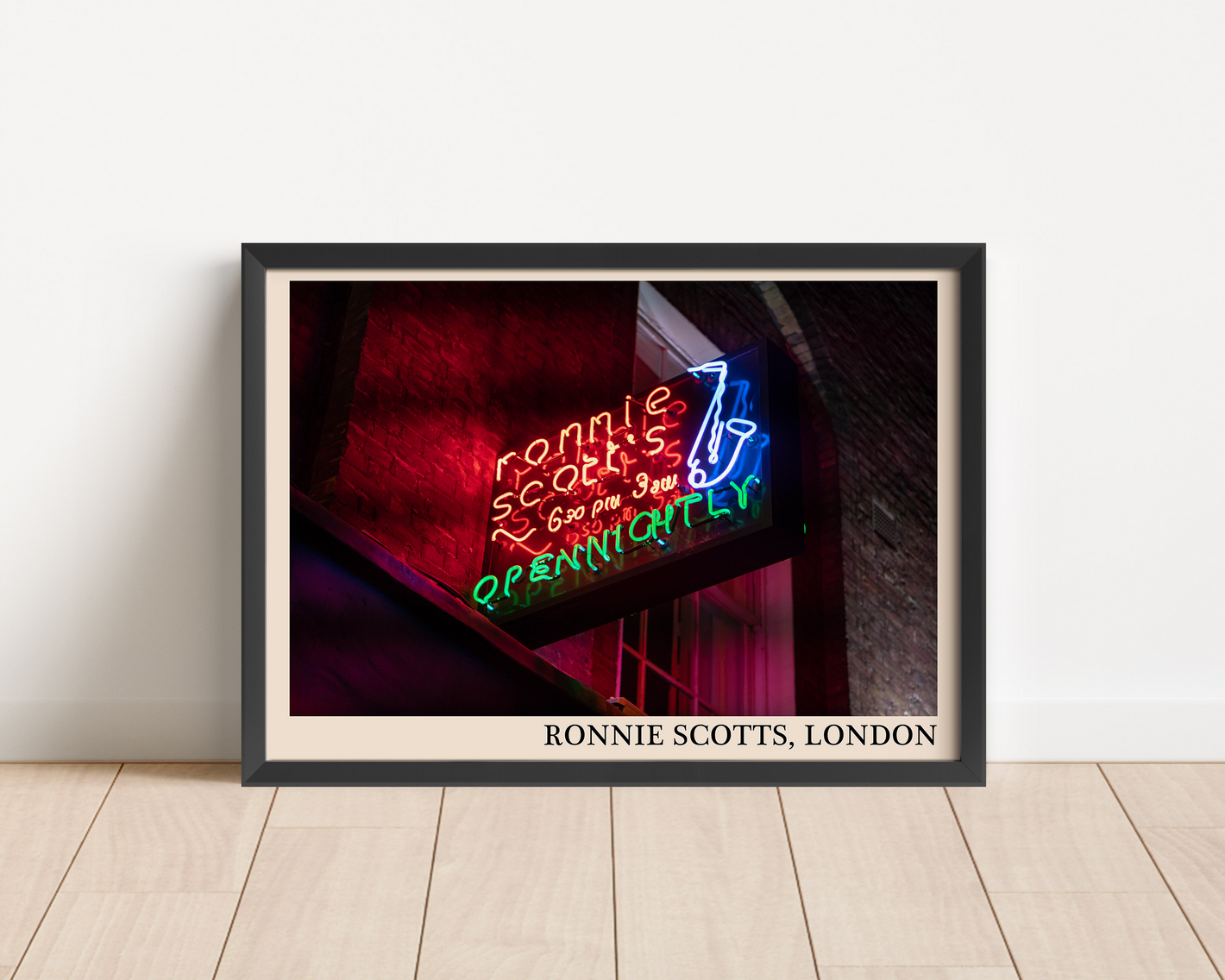 Iconic photo of Ronnie Scotts jazz club in London. Picture crafted into a black framed poster, with an off-white border. Poster is propped against a white wall