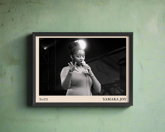 2022 photo of Samara Joy crafted into a black framed-poster, hanging on a light green concrete wall in dappled sunlight