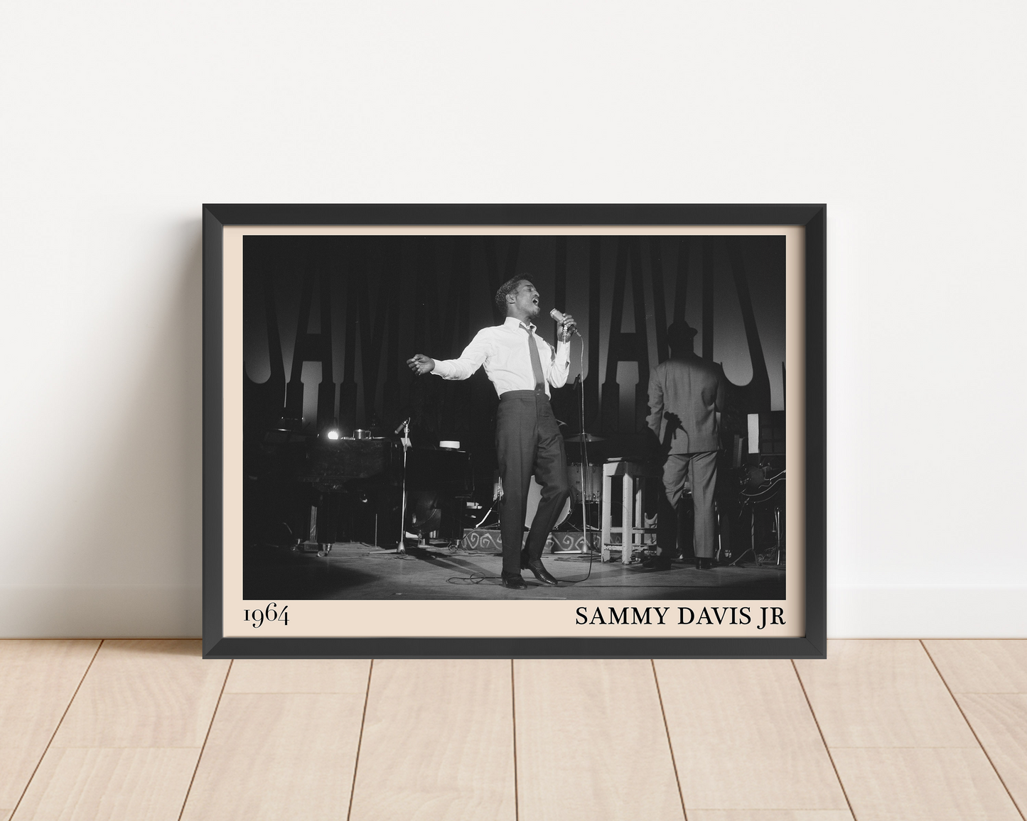 1964 picture of Sammy Davis Jr. Picture crafted into a black framed poster, with an off-white border. Poster is propped against a white wall