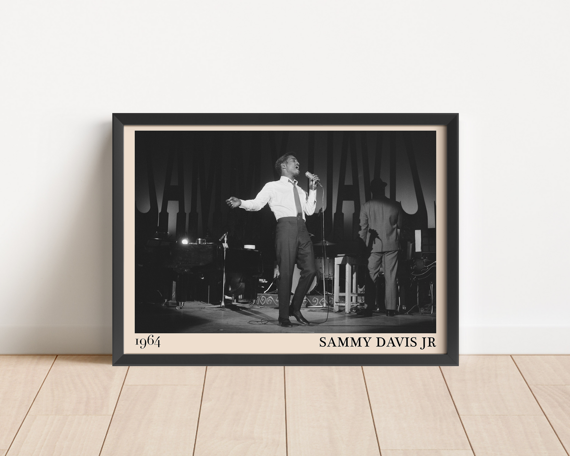 1964 picture of Sammy Davis Jr. Picture crafted into a black framed poster, with an off-white border. Poster is propped against a white wall