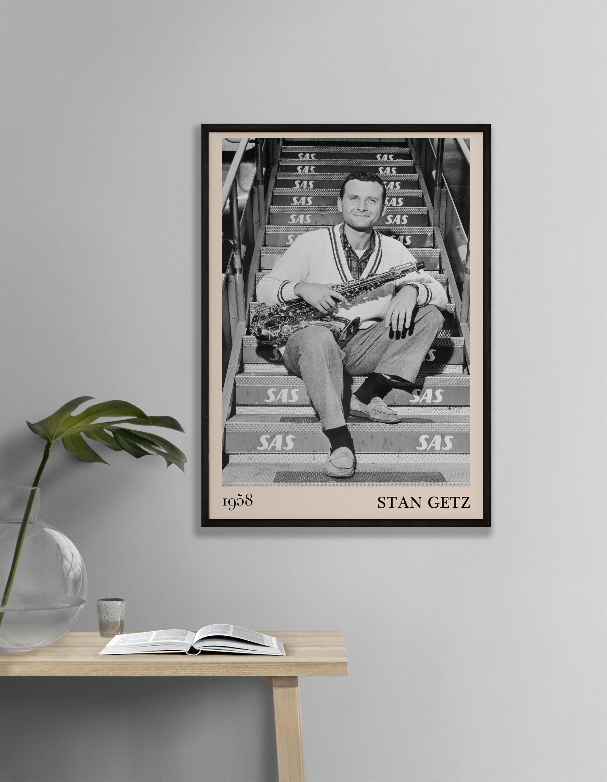 1958 picture of Stan Getz holding his saxophone. Picture crafted into a cool black framed jazz print, with an off-white border. Poster is hanging on a grey living room wall