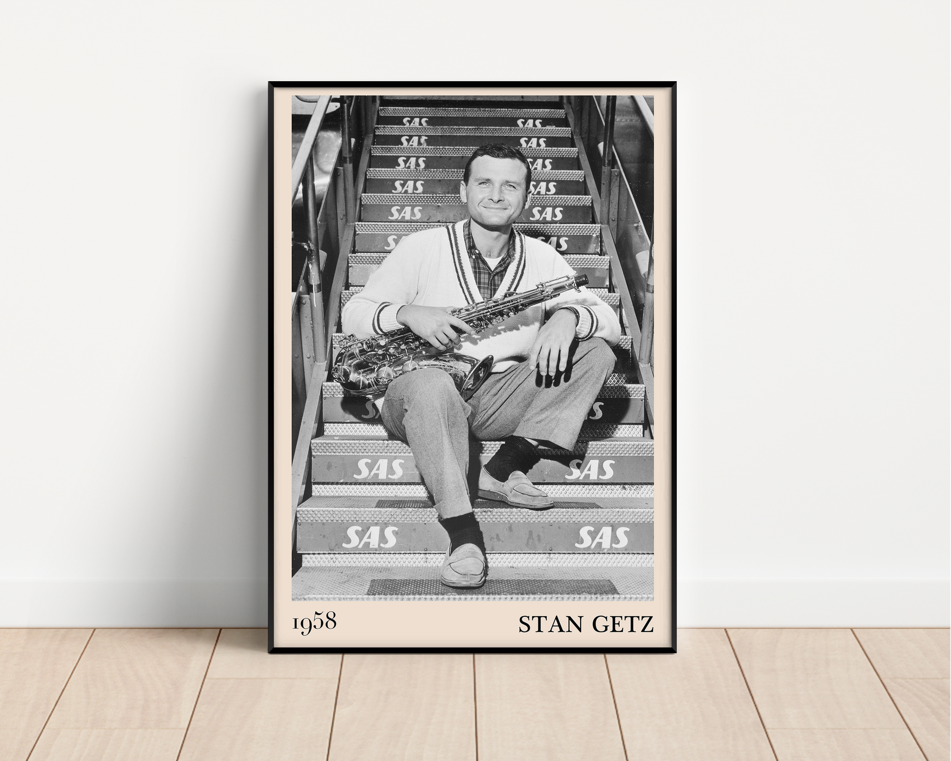 1958 picture of Stan Getz holding his saxophone. Picture crafted into a black framed poster, with an off-white border. Poster is propped against a white wall