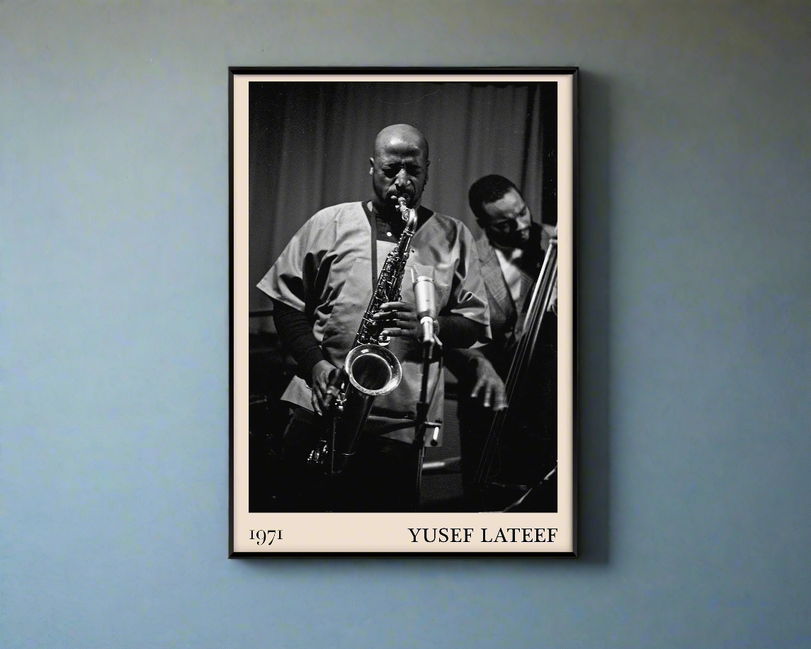 1971 photo of Yusef Lateef crafted into a black framed-poster, hanging on a blue rustic concrete wall in dappled sunlight 