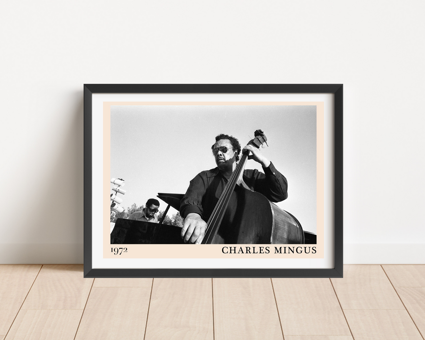 Charles Mingus Cool Jazz Poster in landscape main mount mockup, black frame, vintage 1972 jazz design on wood floor.