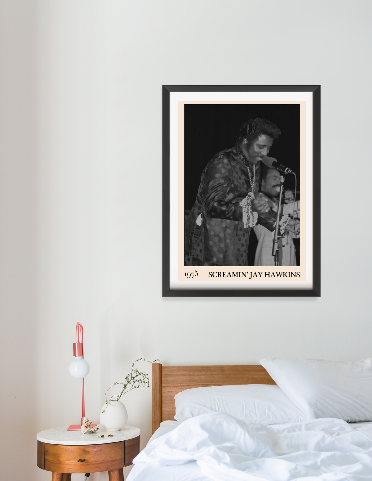 Framed print of Screamin Jay Hawkins performing live in 1975, hung above a wooden bed in a minimal bedroom setting.