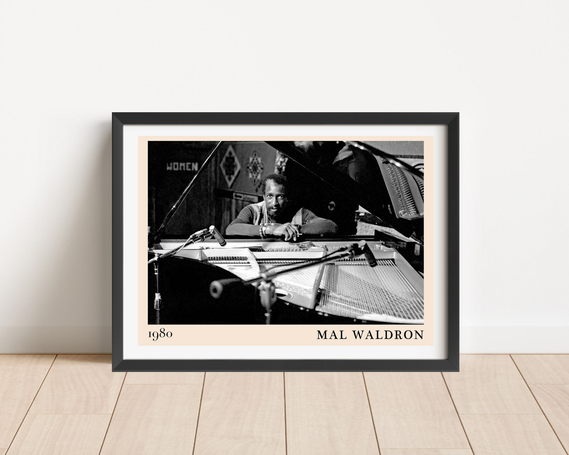 Mal Waldron Jazz Poster in landscape frame mockup, black and white piano scene, minimalist design on wood floor.