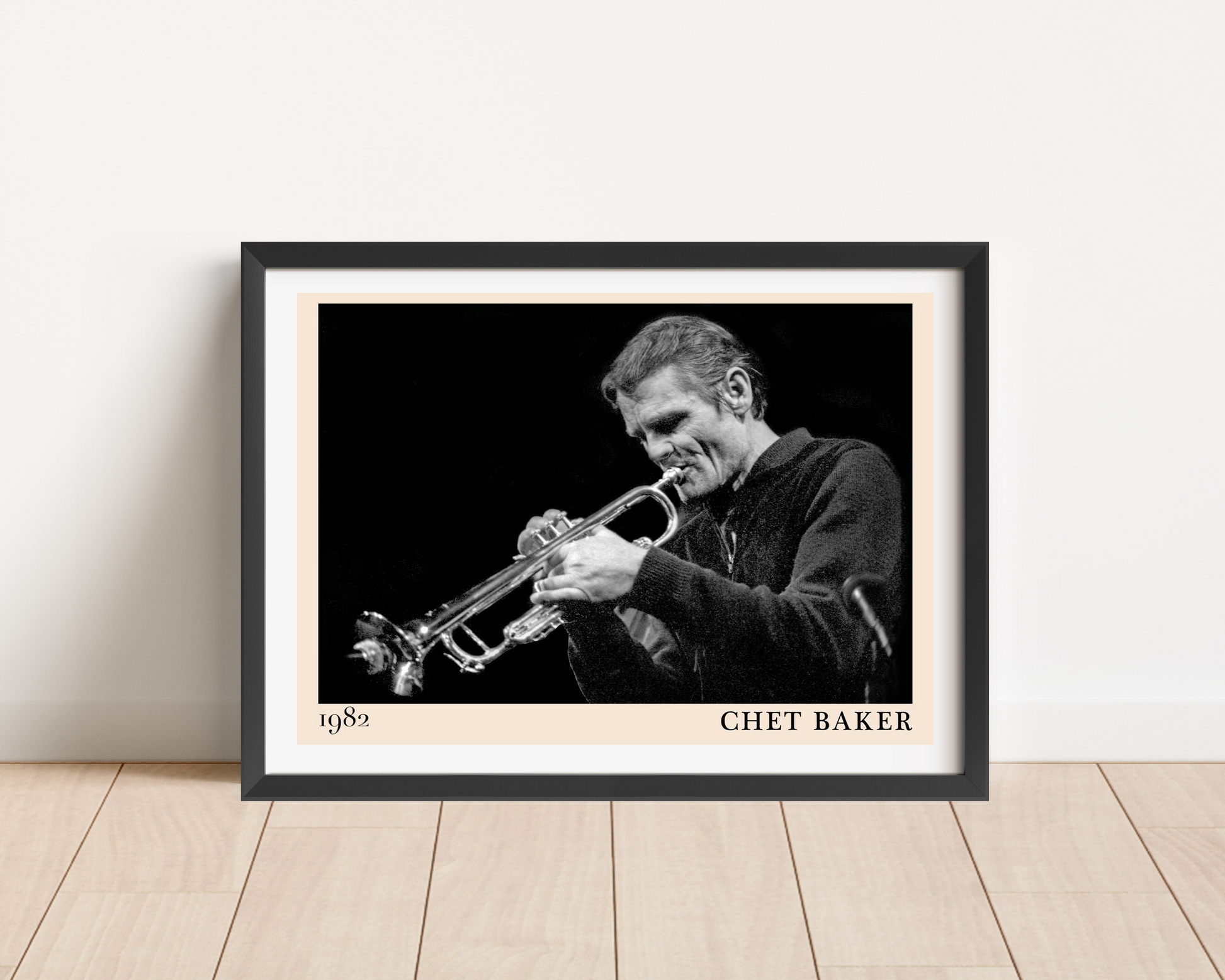 Chet Baker Concert Poster in landscape frame mockup, black and white trumpet design, set on wood floor against white wall.