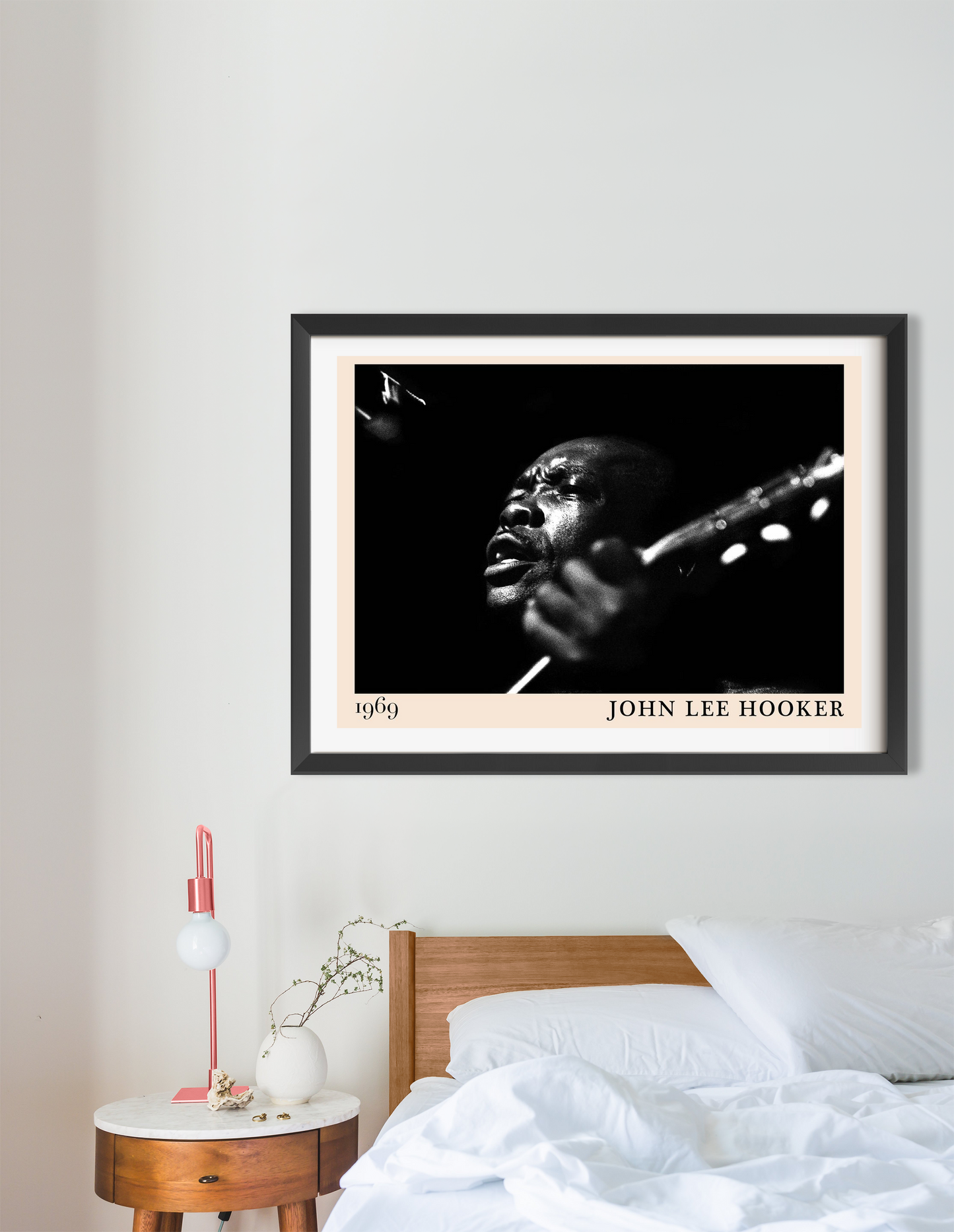John Lee Hooker Retro Blues Poster in a black frame, landscape 16 mount, above a modern bed with white bedding and wood decor