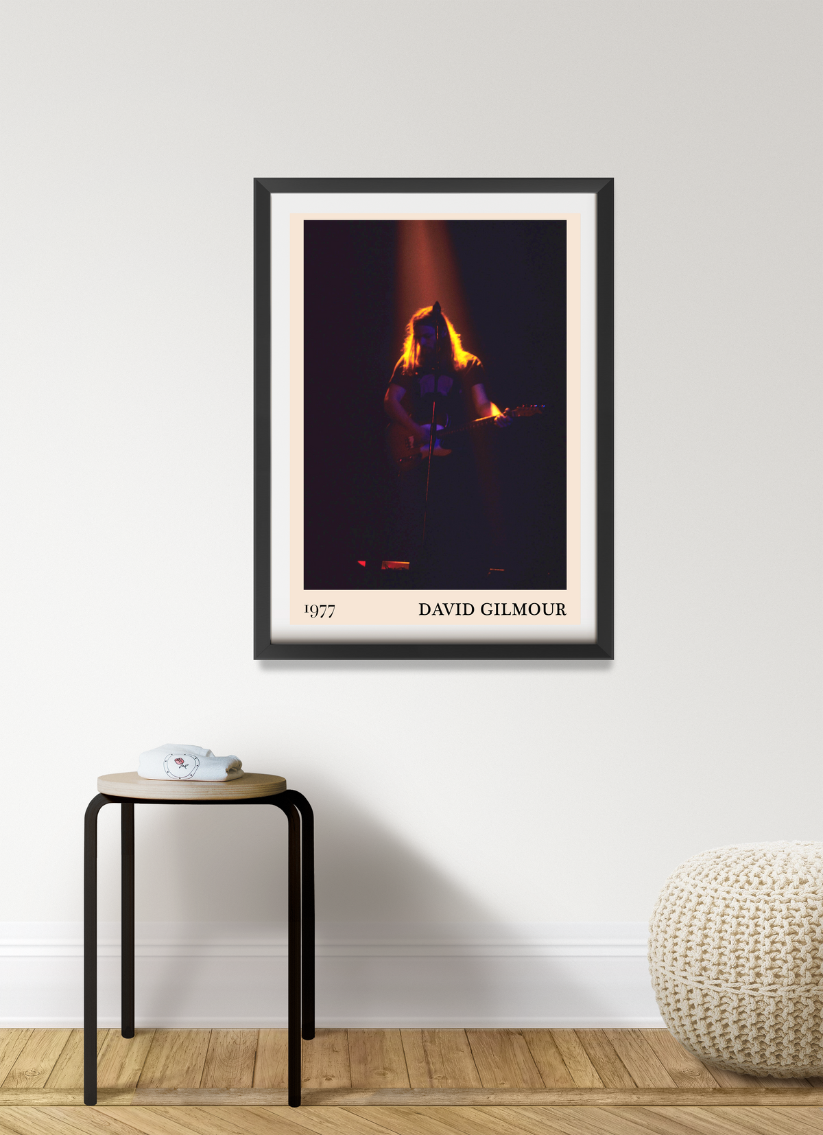 David Gilmour 1977 framed print in black frame with white mount, hung on a pale wall above a small wooden stool