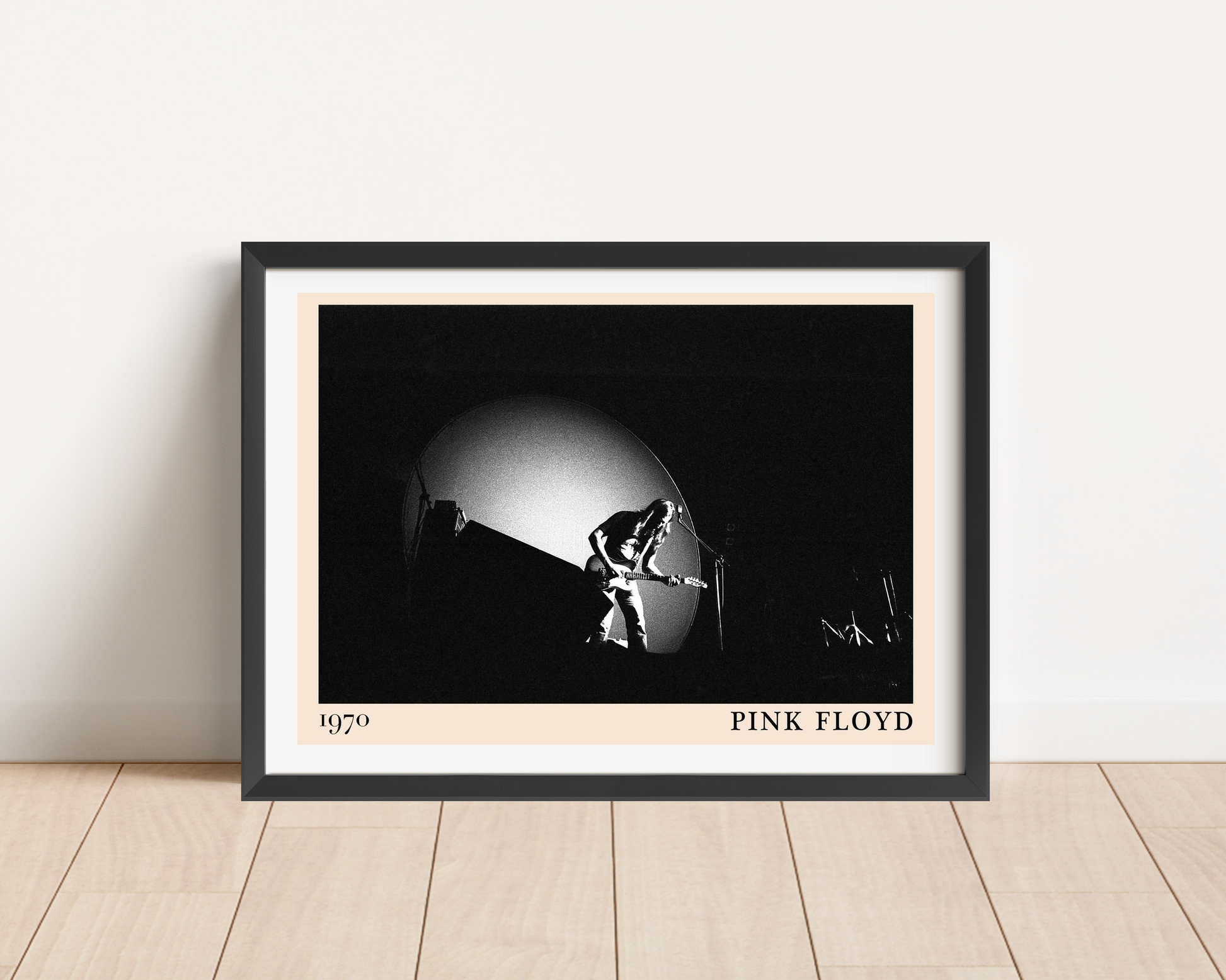 Pink Floyd Retro Rock Poster in landscape frame mockup, black and white 1970 concert photo on wood floor against white wall